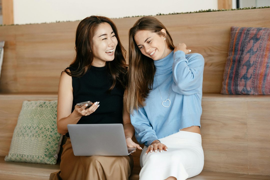 Two women laughing while looking at a laptop | Source: Pexels