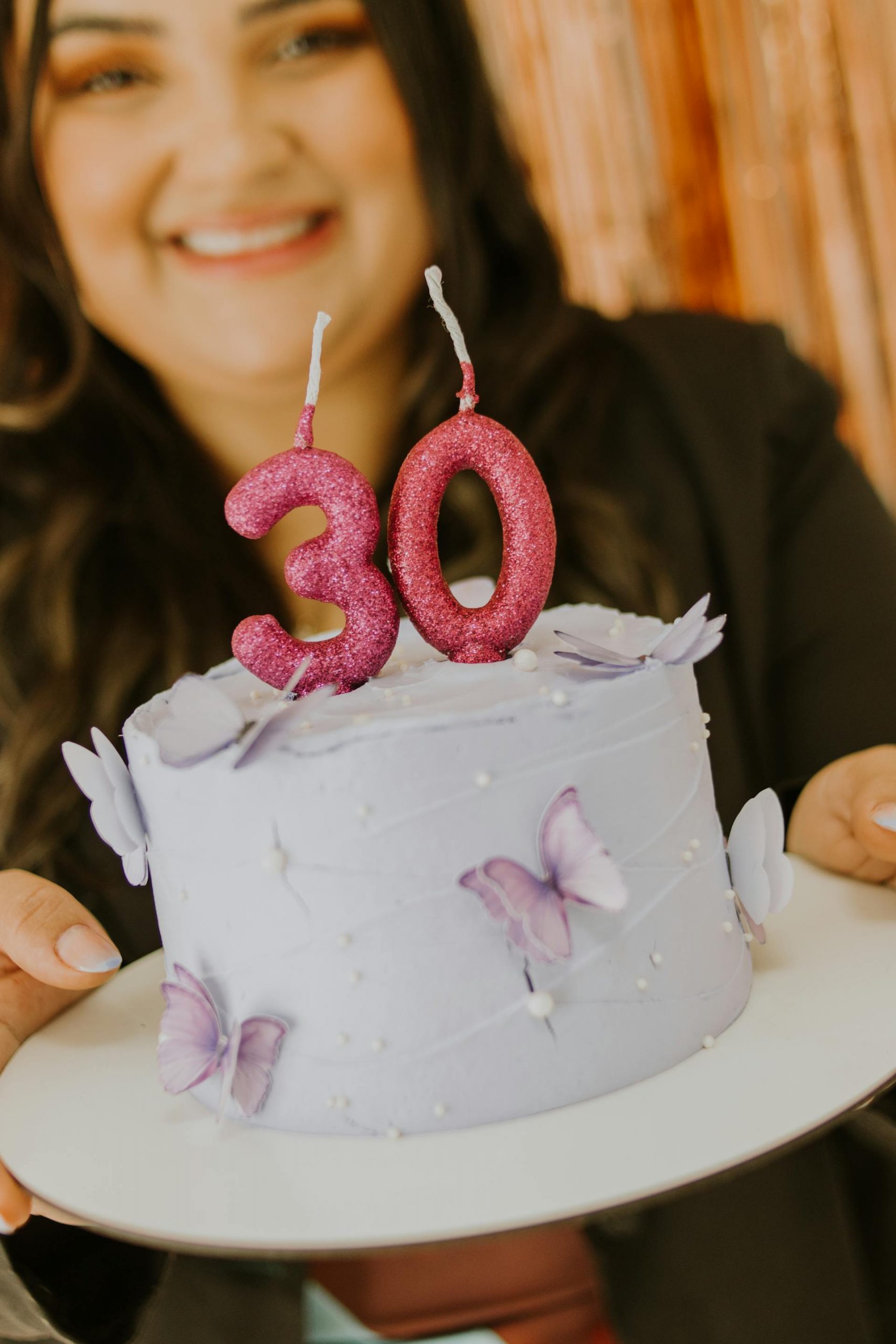 A woman holding a purple birthday cake | Source: Pexels