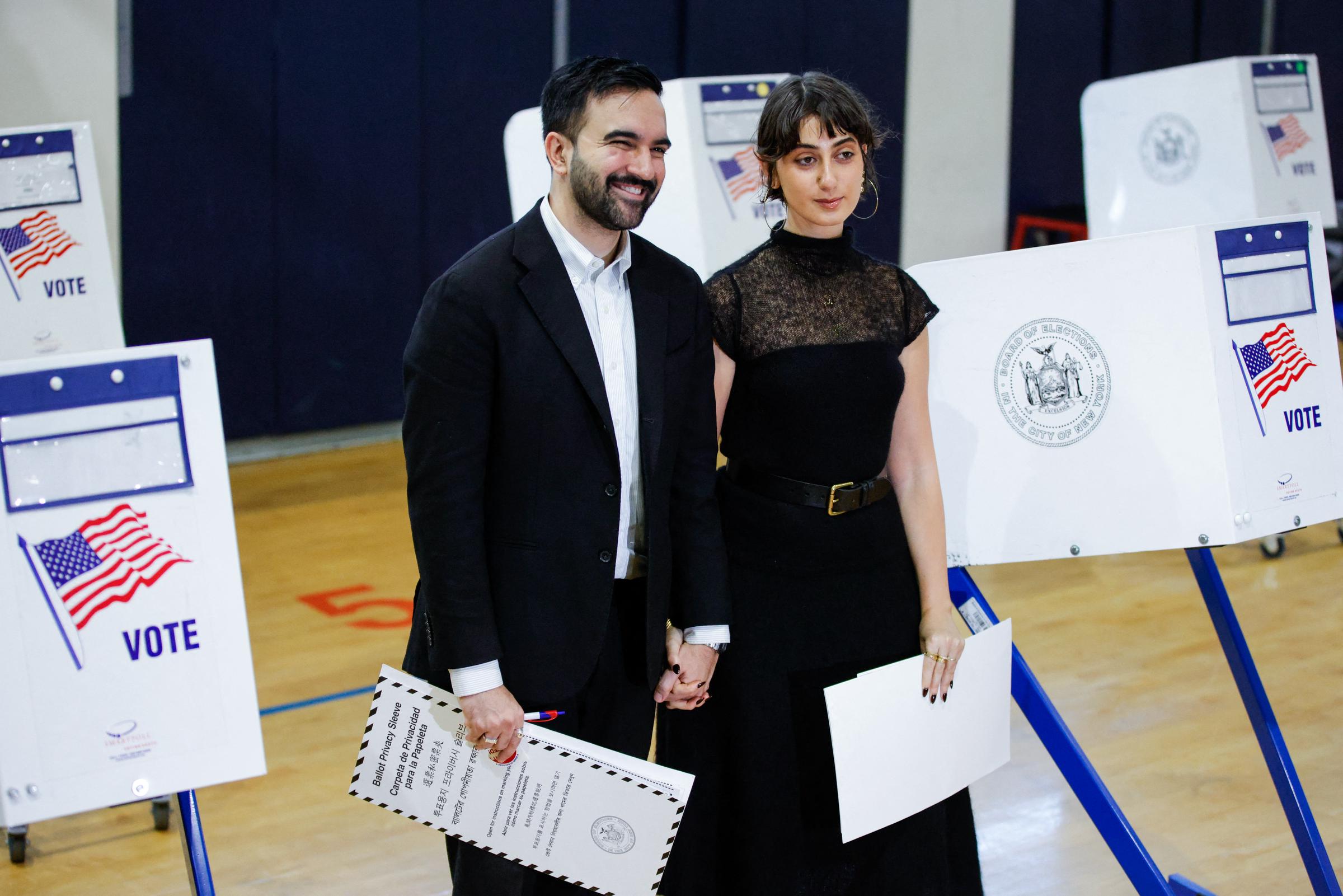 Hand in hand and holding their ballots, Zohra Mamdani and Rama Duwaji walk through a Queens polling station, sharing a quiet but powerful moment on Election Day in New York City.