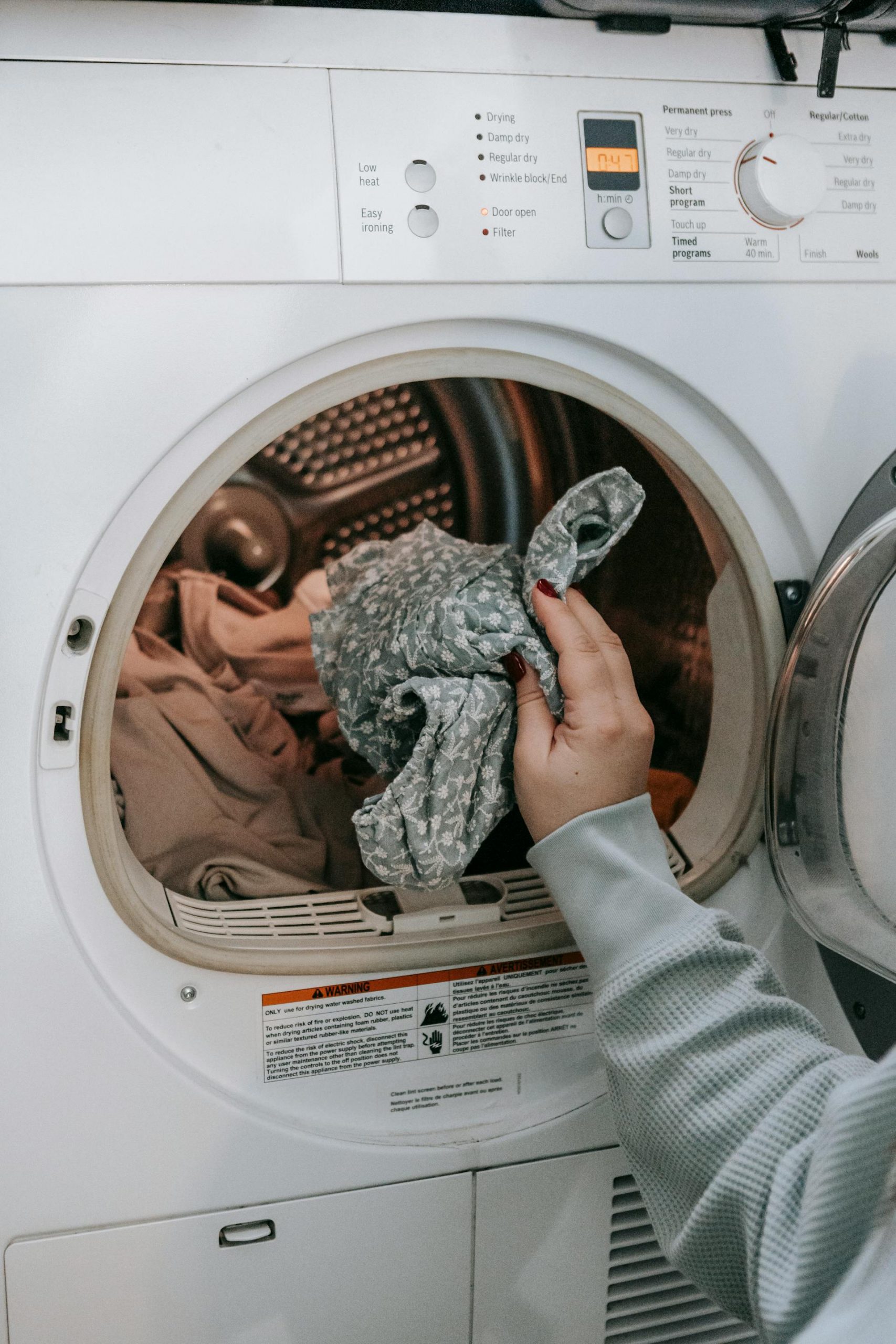 A woman putting clothes in a washing machine | Source: Pexels