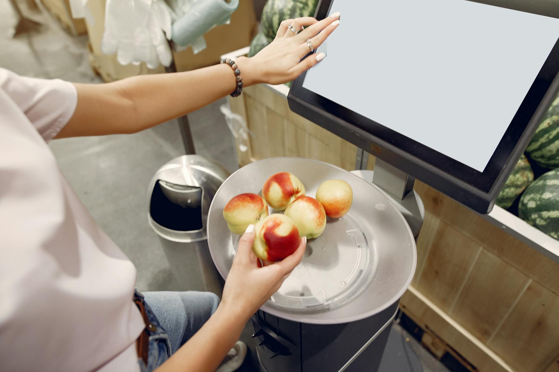 A woman weighing peaches on a scale in a grocery store | Source: Pexels