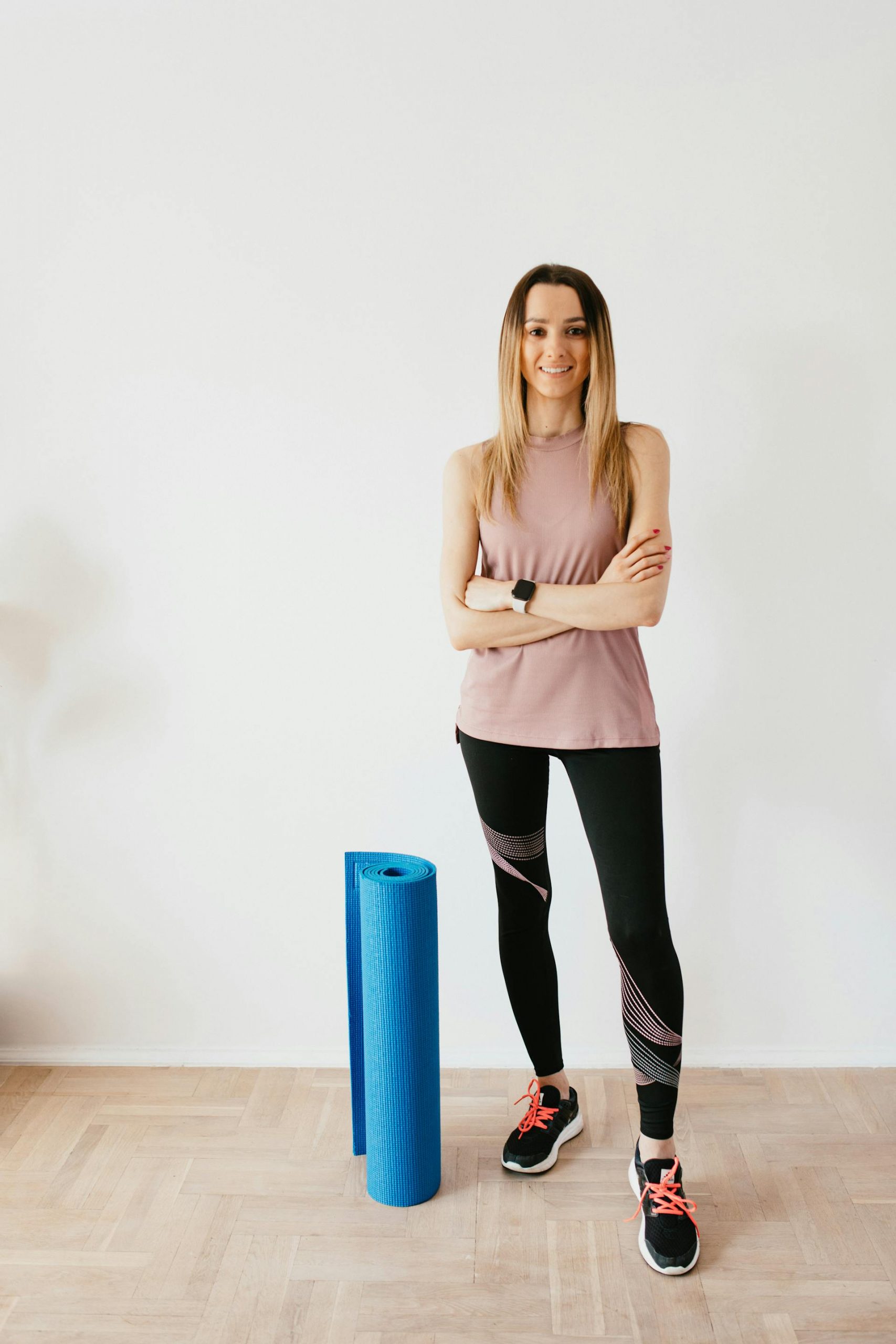 A fitness instructor standing next to a folded yoga mat | Source: Pexels