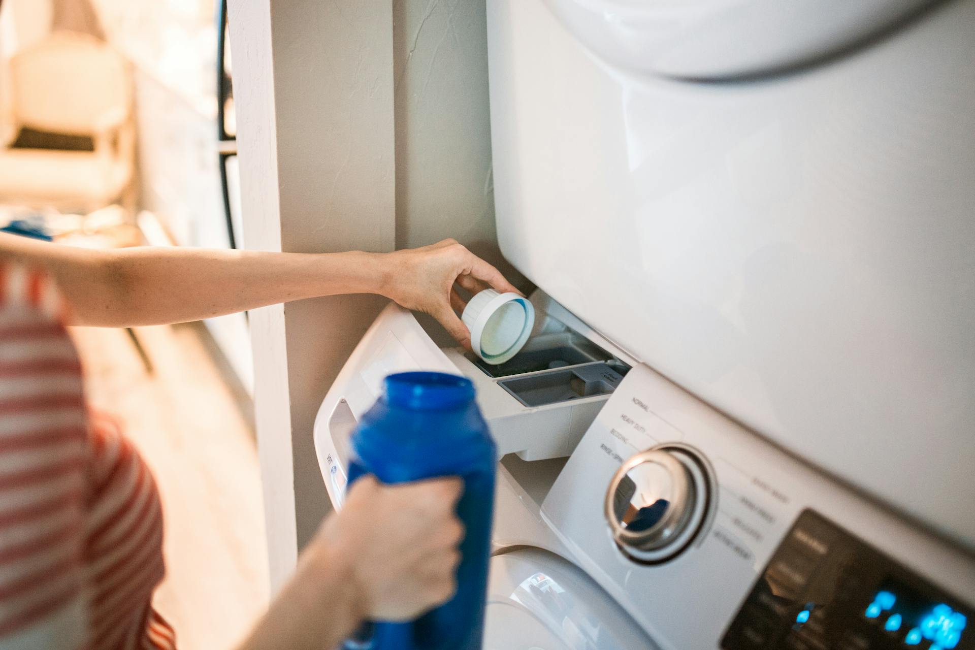 A woman pouring detergent in a washing machine | Source: Pexels