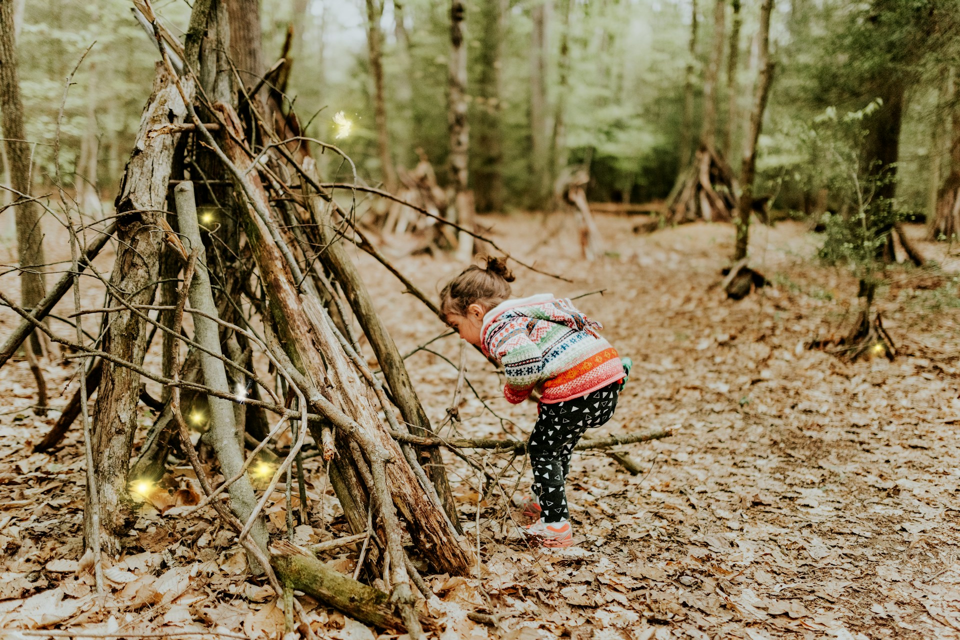 A little girl standing near a pile of sticks | Source: Unsplash