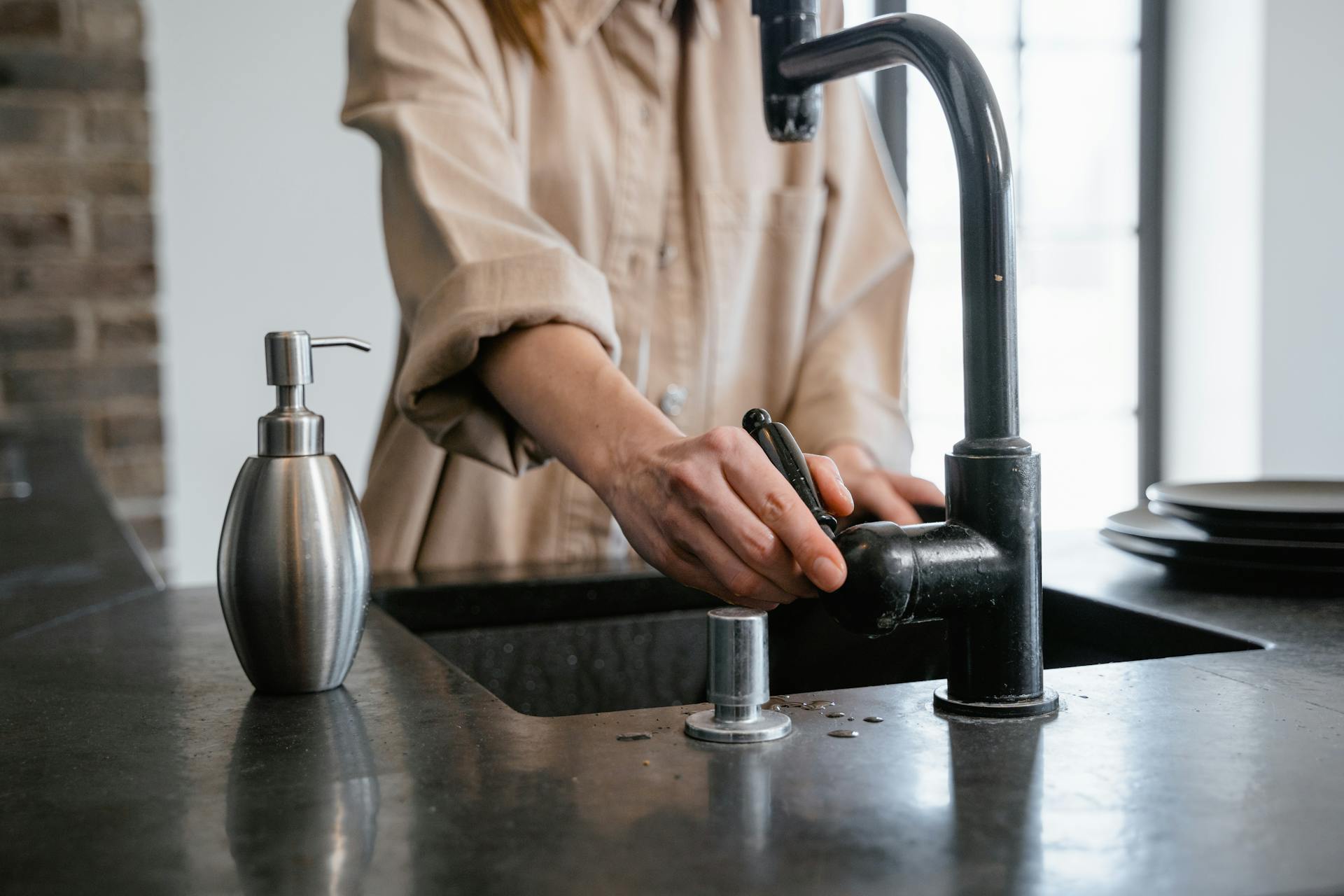 A person opening a kitchen faucet | Source: Pexels