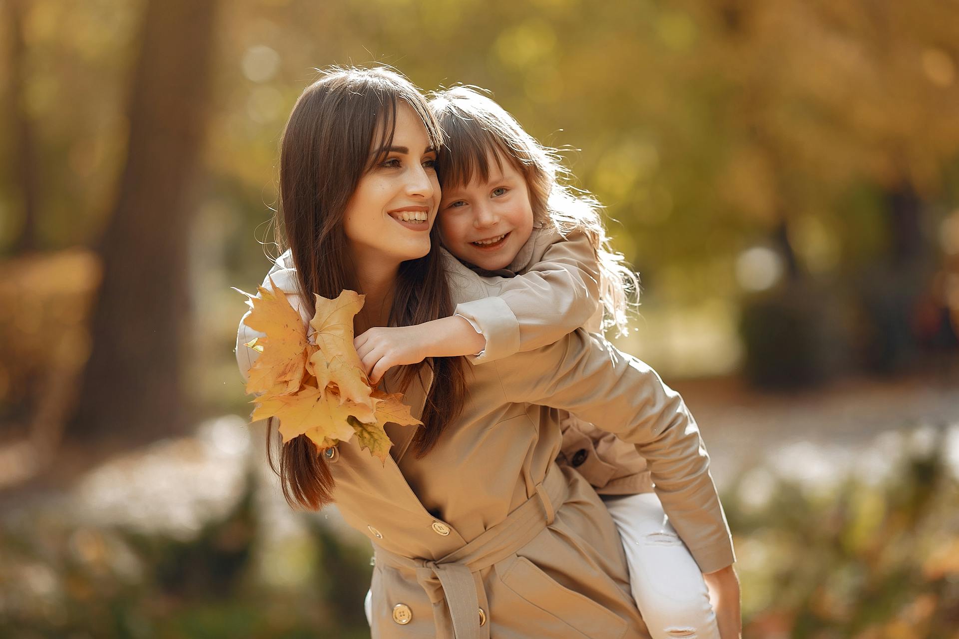 A mother giving her daughter a piggyback ride in the park | Source: Pexels