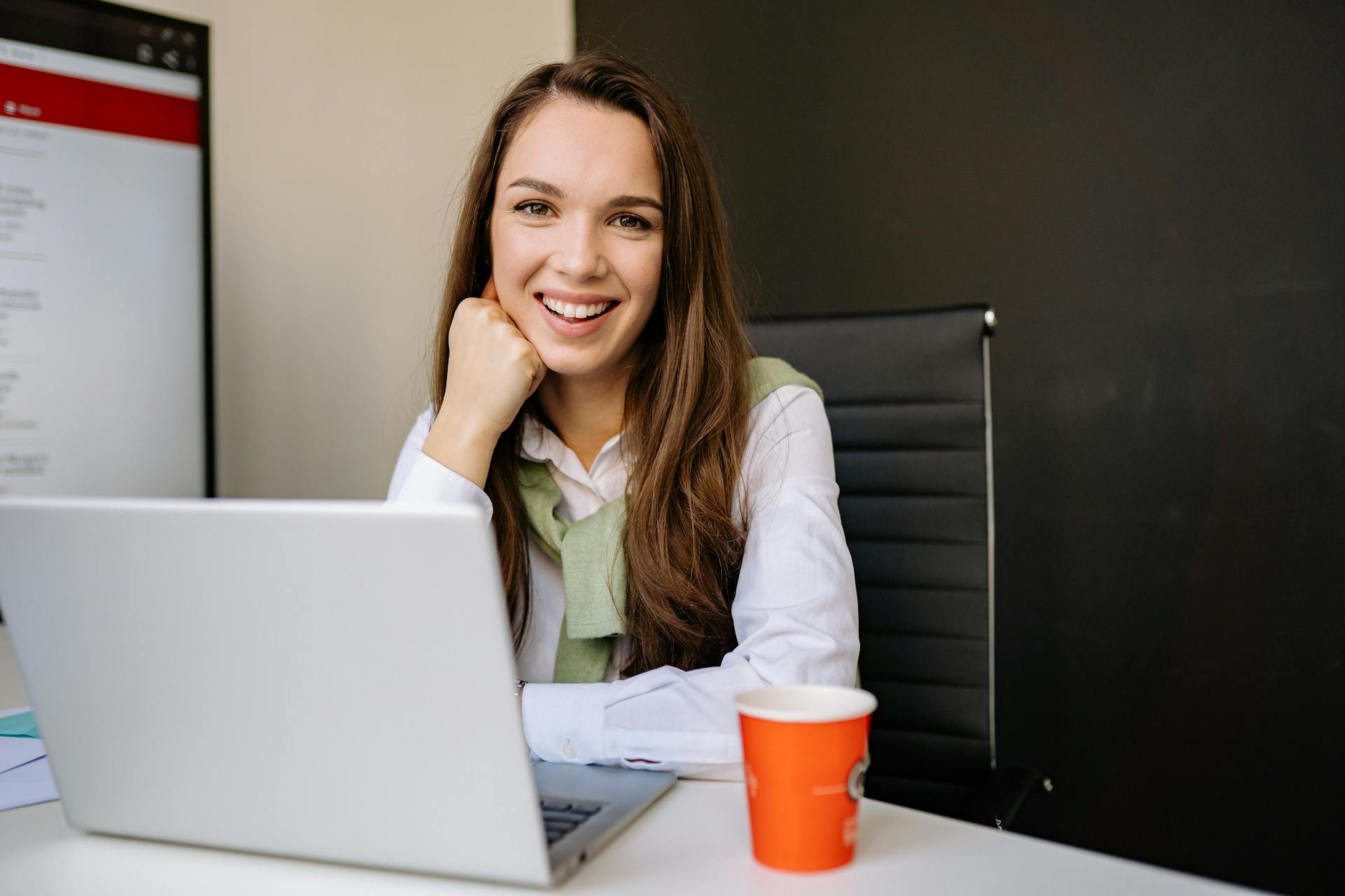 A smiling woman sitting in front of a laptop | Source: Pexels