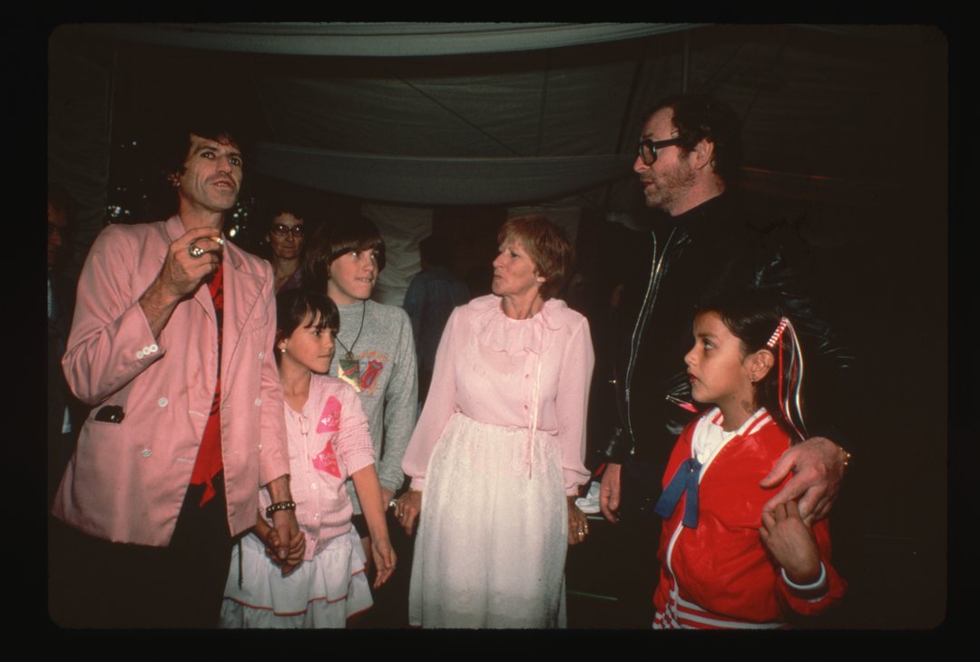 Michael Caine and Natasha pose and chat in 1982 with friends, including Rolling Stones guitarist Keith Richards, who holds his daughter Angela's hand. Also pictured are Richards' son Marlon and mother Doris, as the group enjoys a lively moment together.