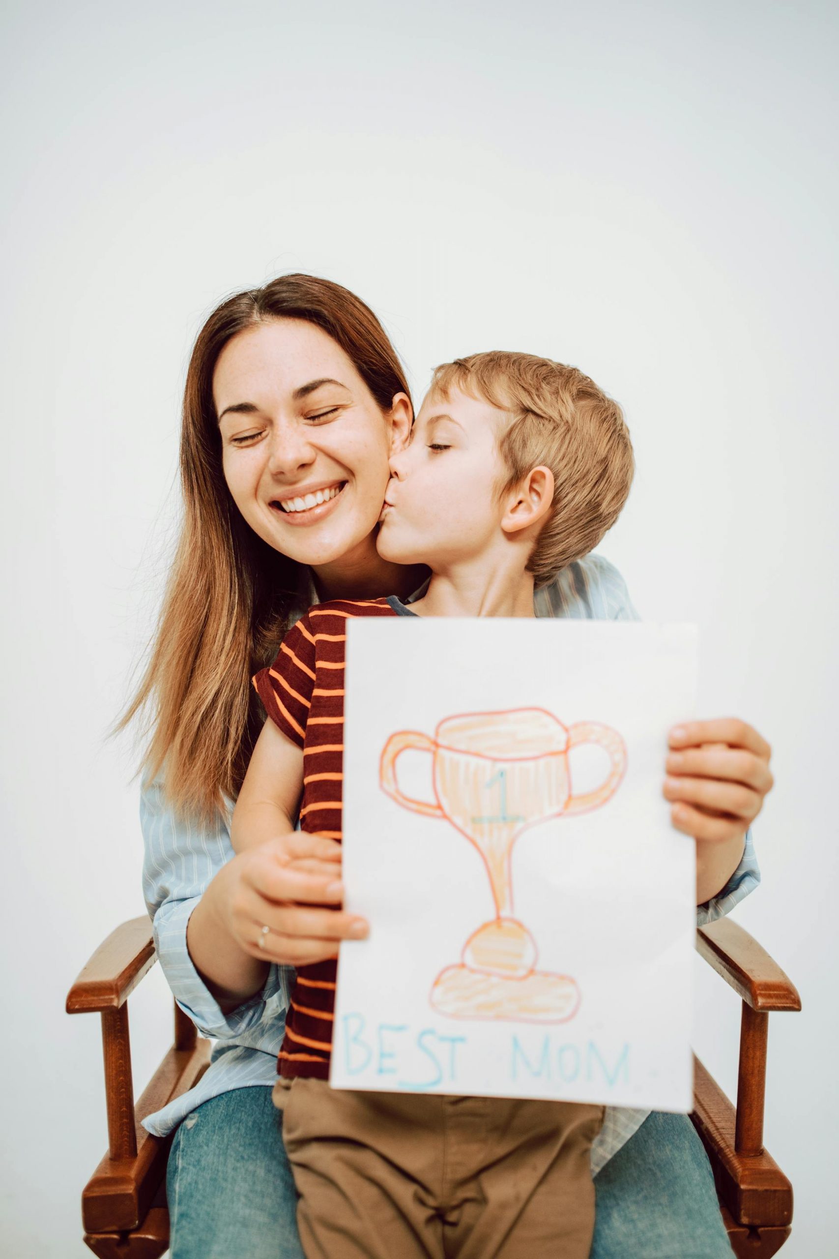 A young boy kissing his mother while holding a drawing on a piece of paper | Source: Pexels