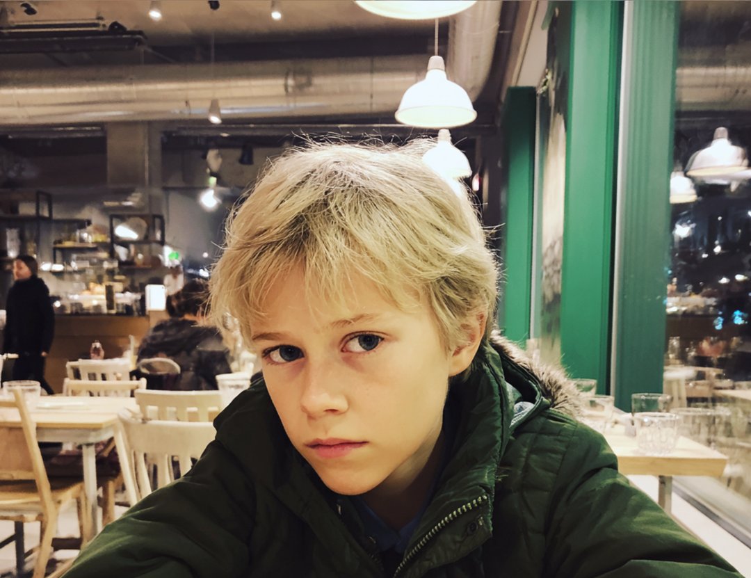 A close-up of a boy sitting at a table | Source: Midjourney