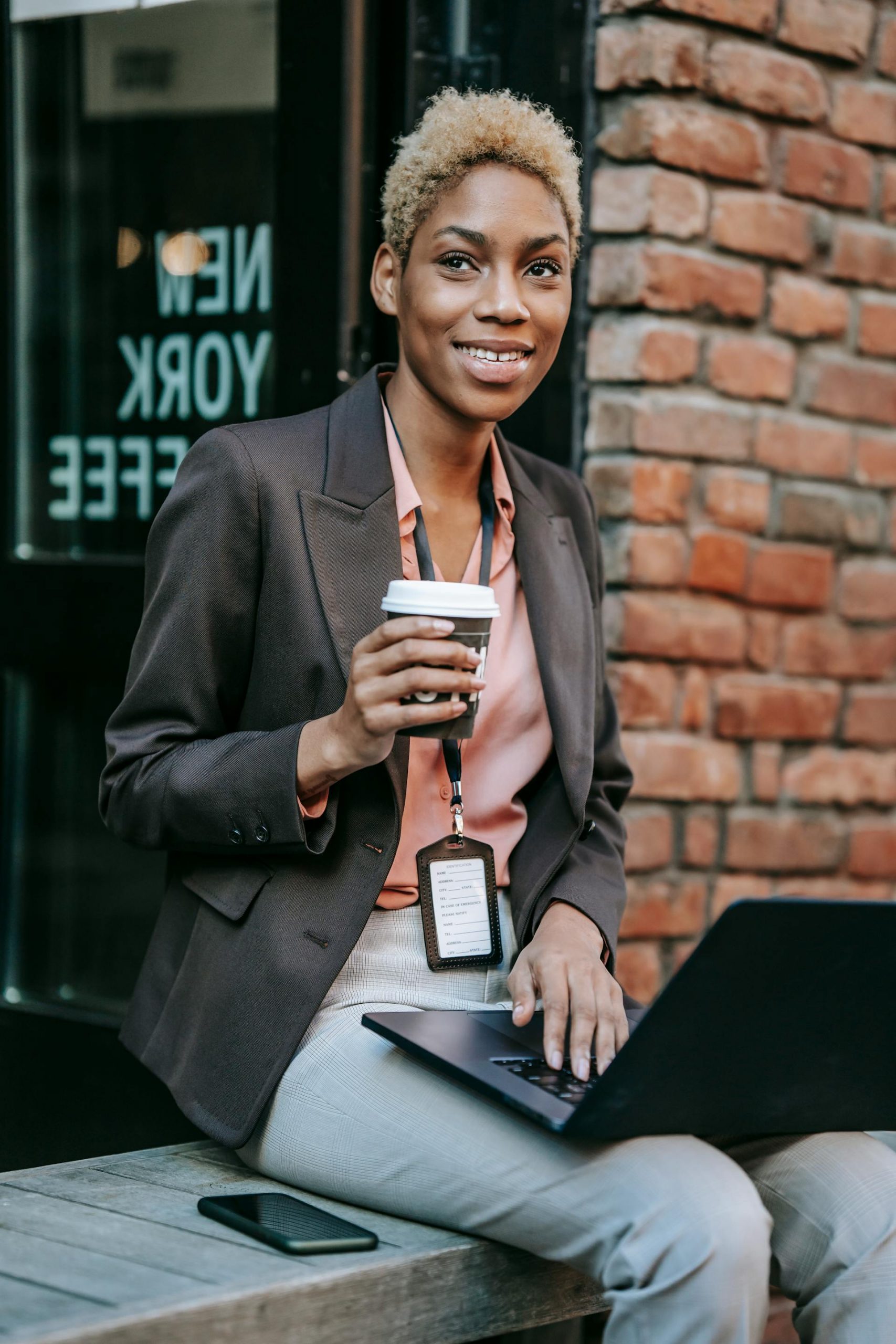 A woman drinking coffee while working on her laptop outside a café | Source: Pexels