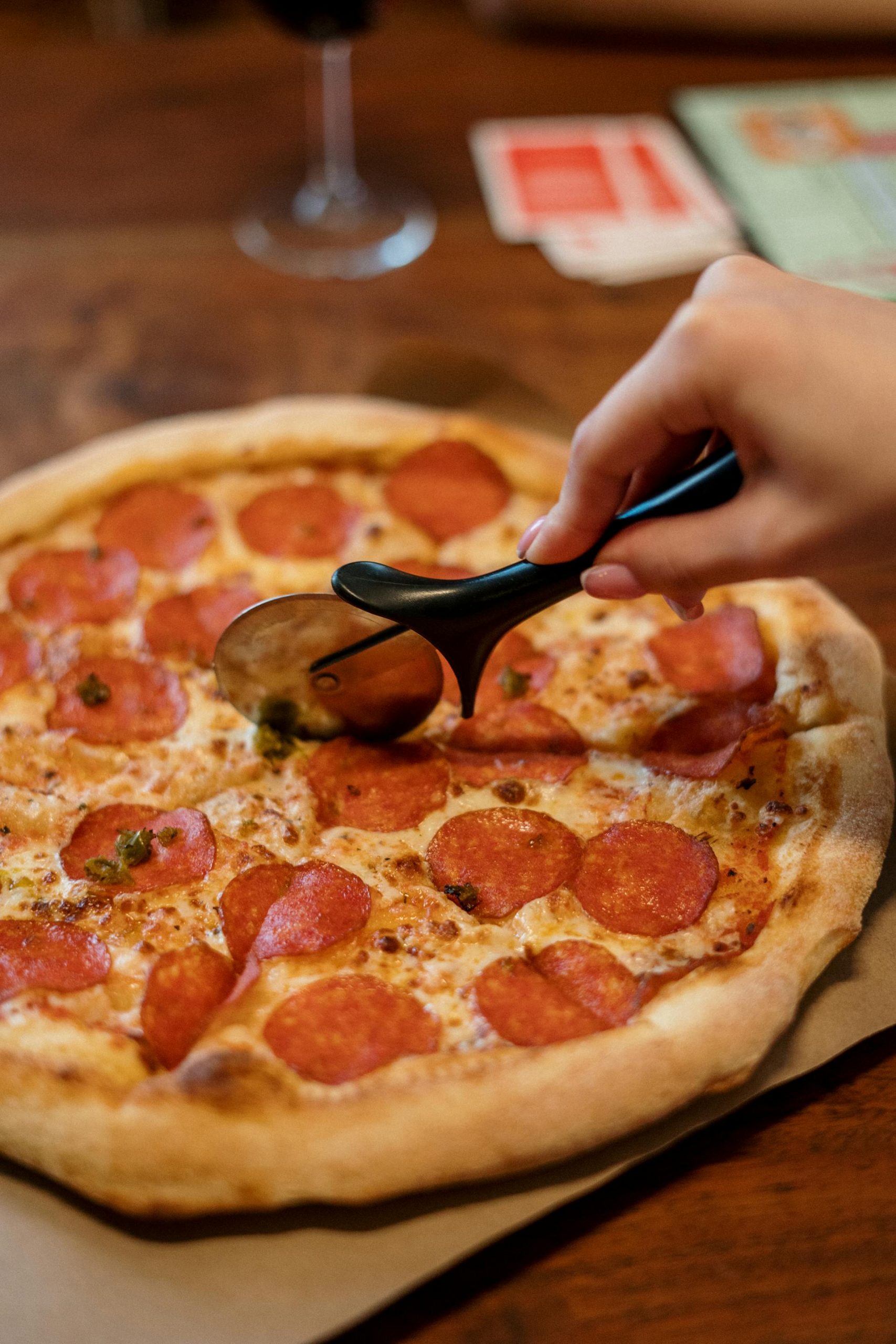 Close-up shot of a person slicing a pizza | Source: Pexels