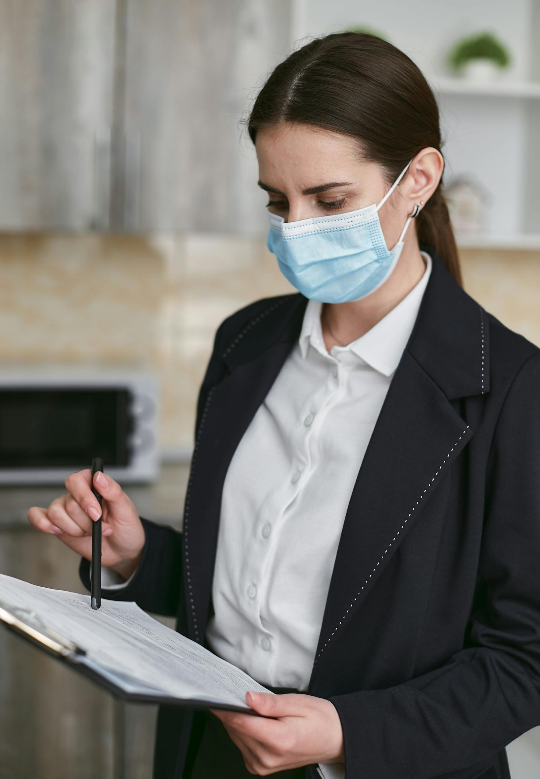 A woman in a face mask looking at a document | Source: Pexels