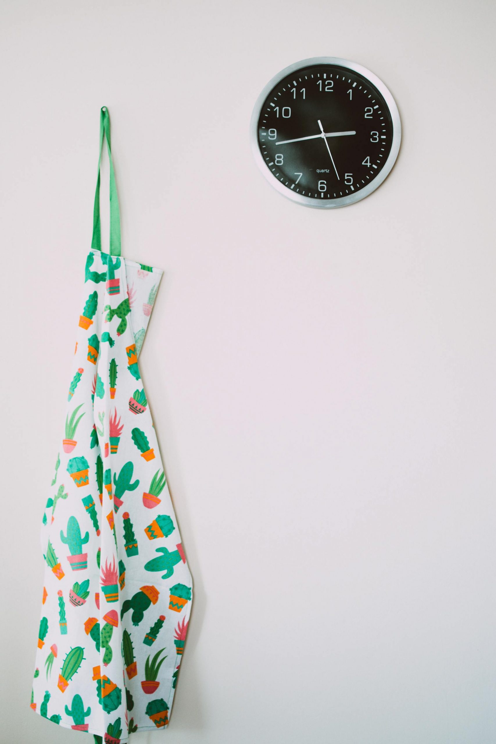 An apron hanging from a wall with an analog clock close to it | Source: Pexels