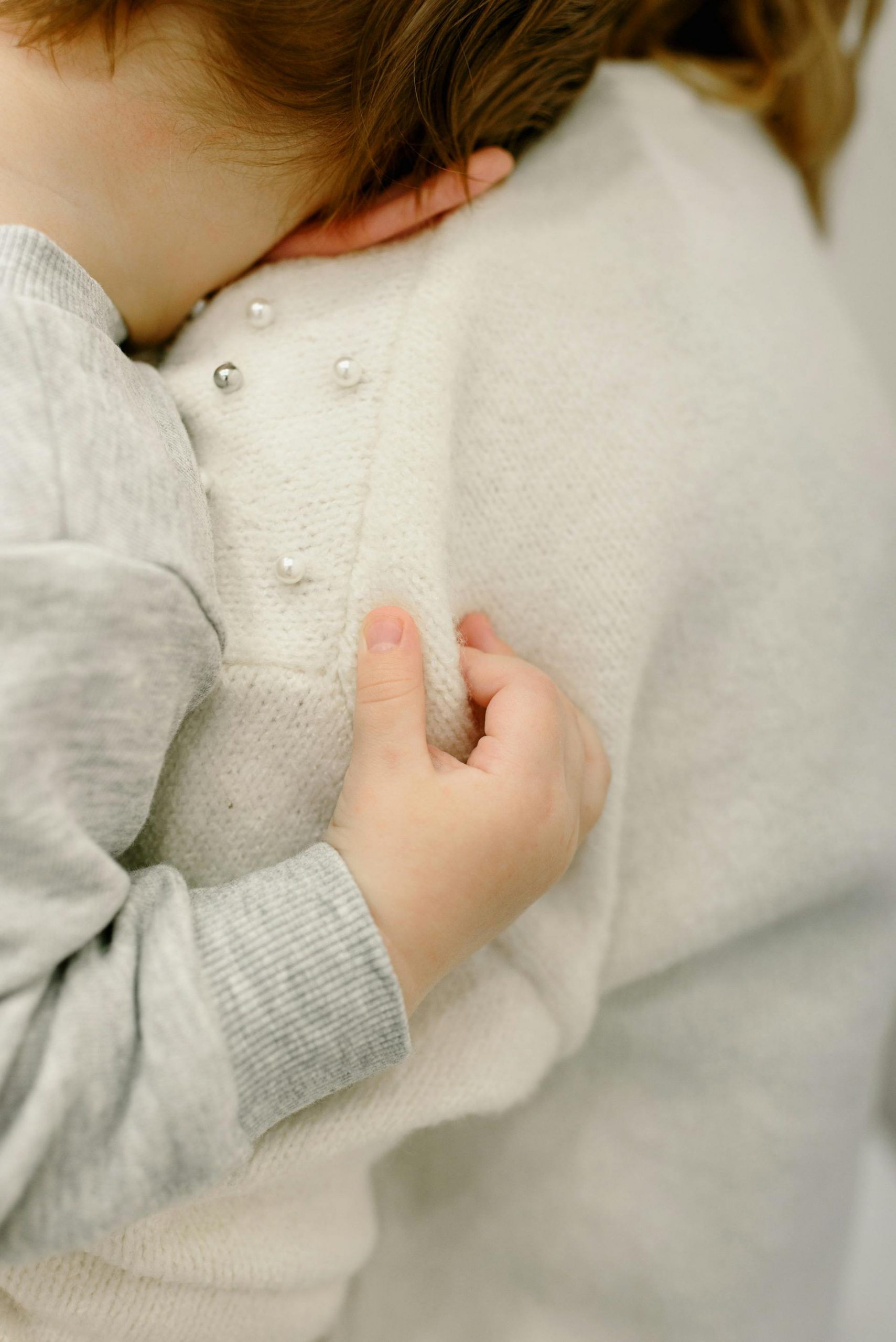 A toddler leaning on their mom's shoulder | Source: Pexels