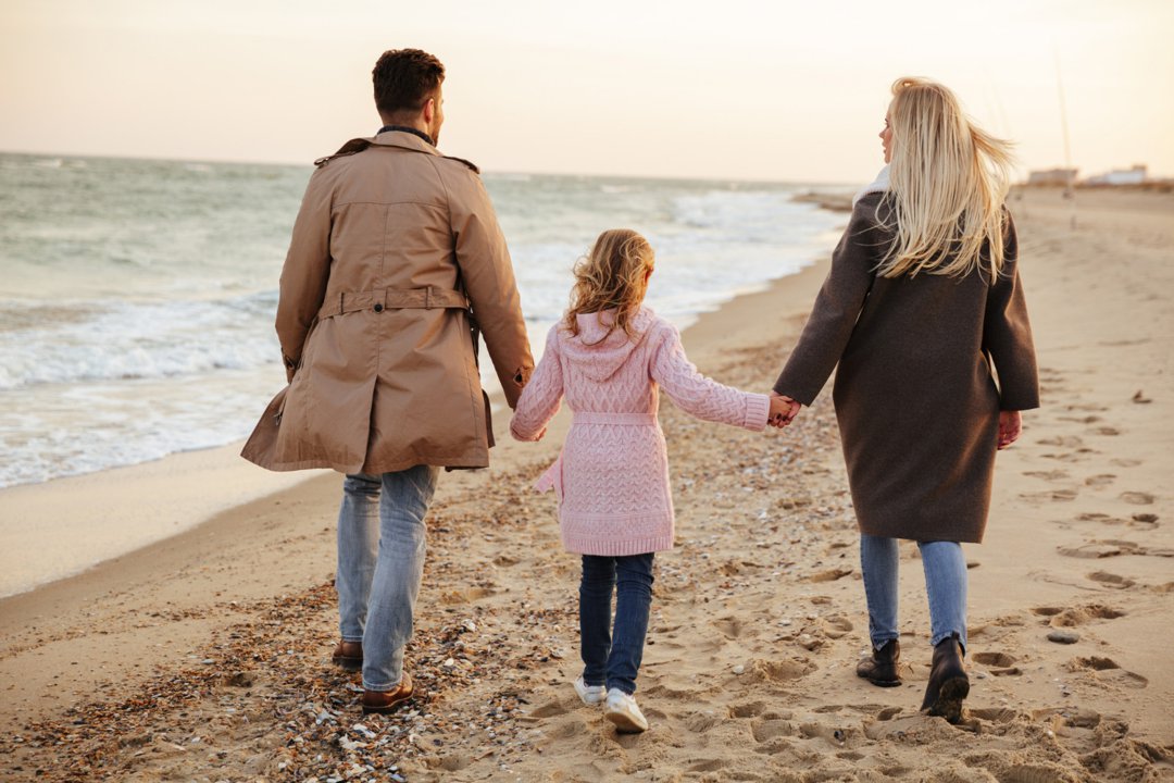 A couple with their daughter on the beach | Source: Freepik
