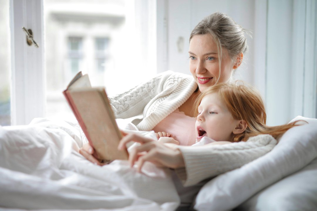 A mother reading to her daughter in bed | Source: Pexels