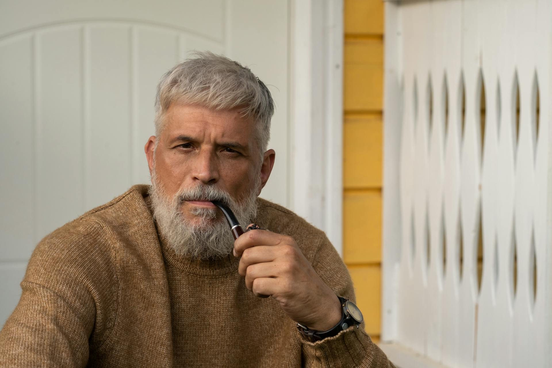 A sad senior man sitting on the porch with a pipe | Source: Pexels