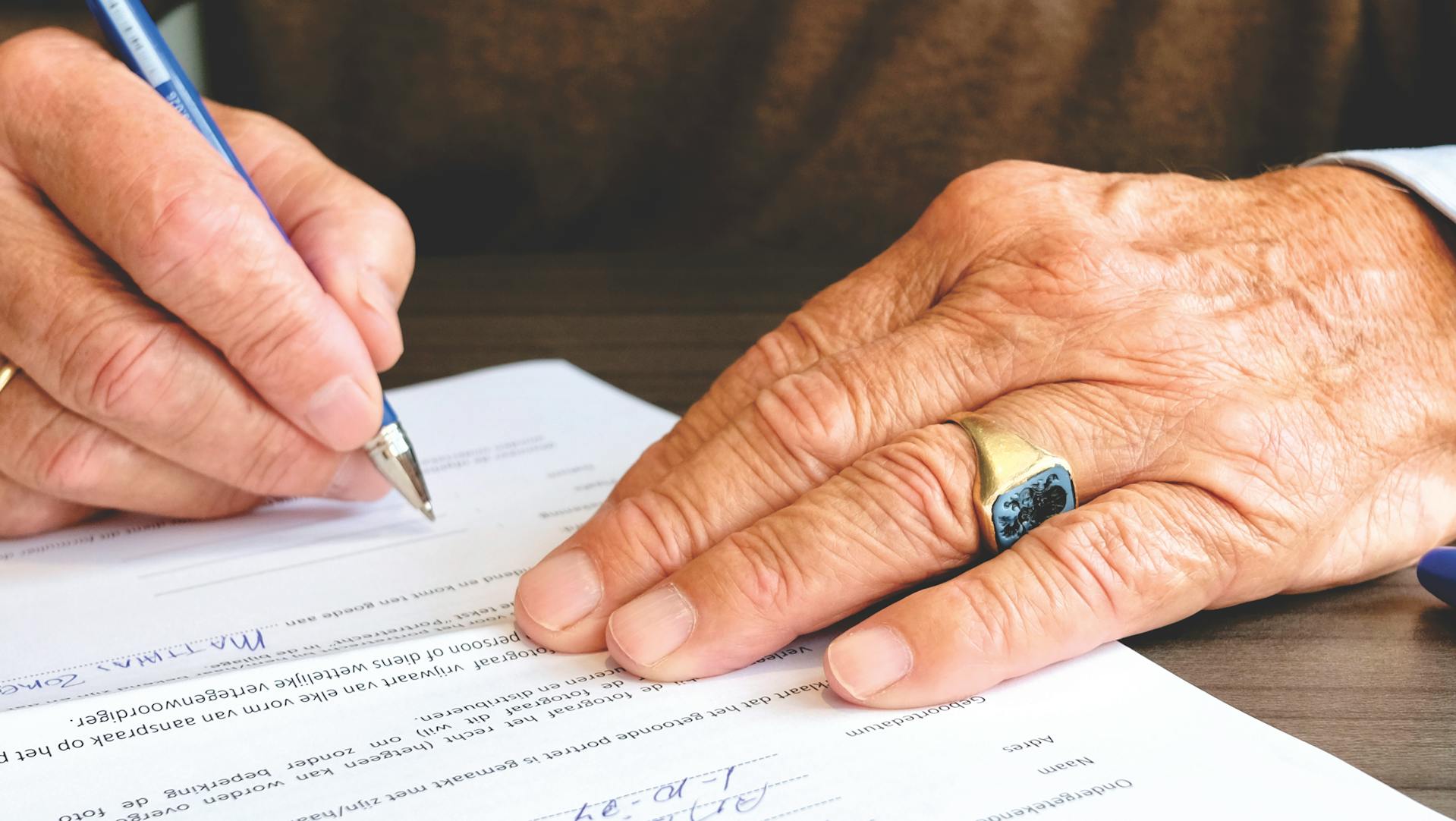 A senior man signing a document | Source: Pexels