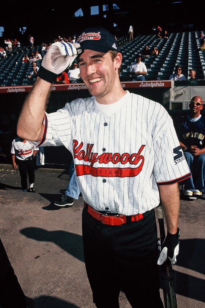 James Van Der Beek tips his cap with a bright grin at a celebrity All-Star softball game. In a pinstriped “Hollywood Allstars” jersey, he blends playful athletic spirit with star charm. Bat in hand, he radiates the relaxed energy of a summer afternoon on the field.