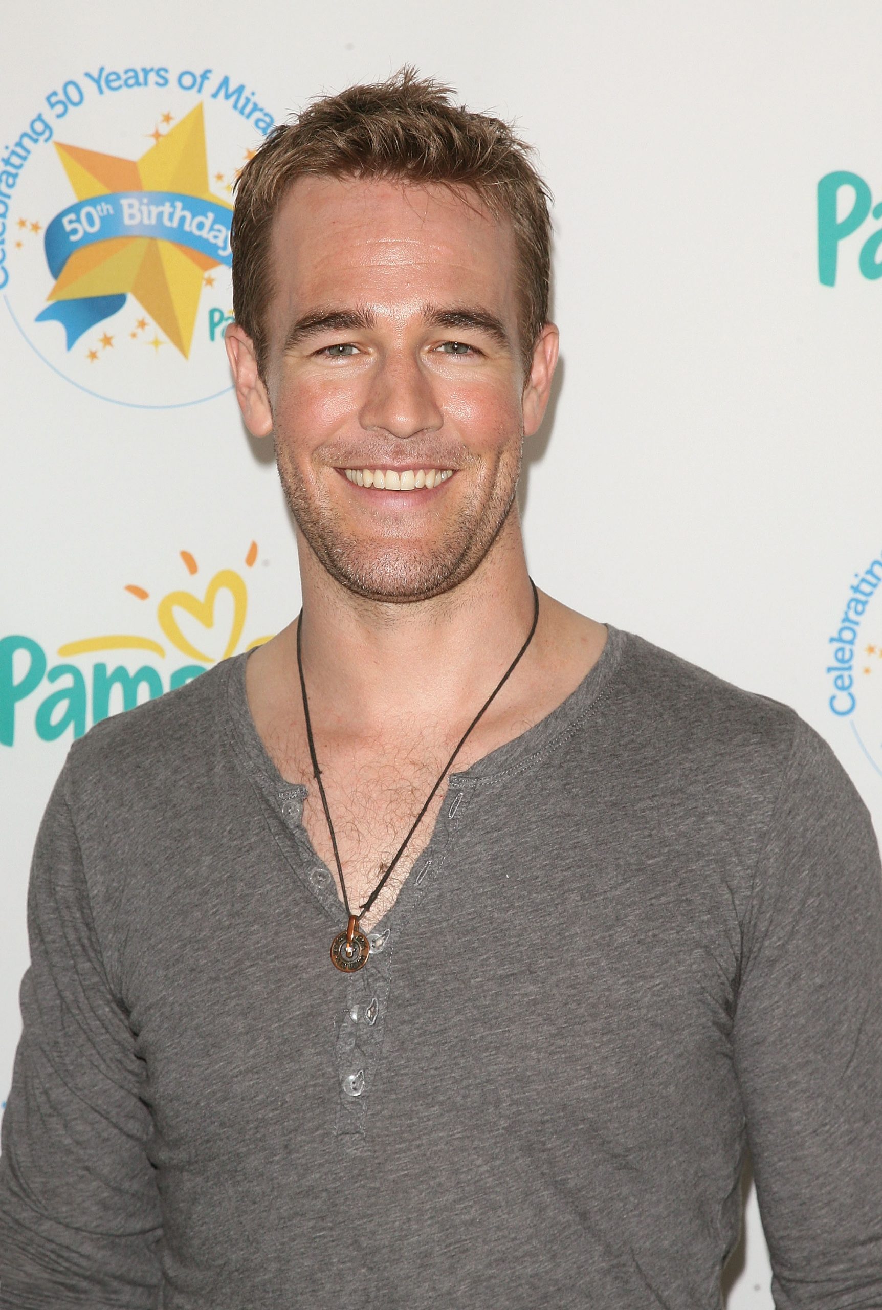 James Van Der Beek steps into the celebration with an easy grin, his casual henley and simple pendant giving him a warm, approachable glow. The soft lighting highlights his relaxed charm, making him look every bit the doting dad-supporter at a family-focused event.