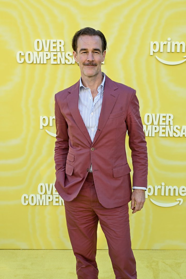 James Van Der Beek steps onto the yellow carpet in a dusty-rose suit that mirrors his effortless confidence and wry charm. His neatly trimmed mustache and relaxed stance give him a cool, vintage edge against the bright backdrop. At the 