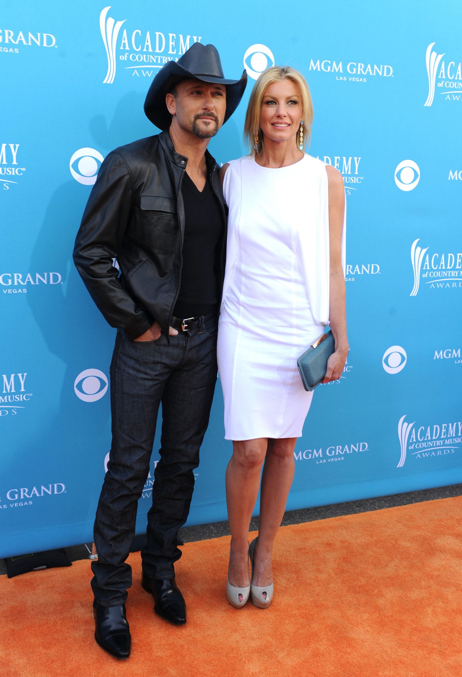 At the Academy of Country Music Awards in Las Vegas, Tim McGraw smolders in leather and jeans while Faith Hill shines in a white dress. Side by side on the orange carpet, they strike a modern pose that blends edge with elegance.