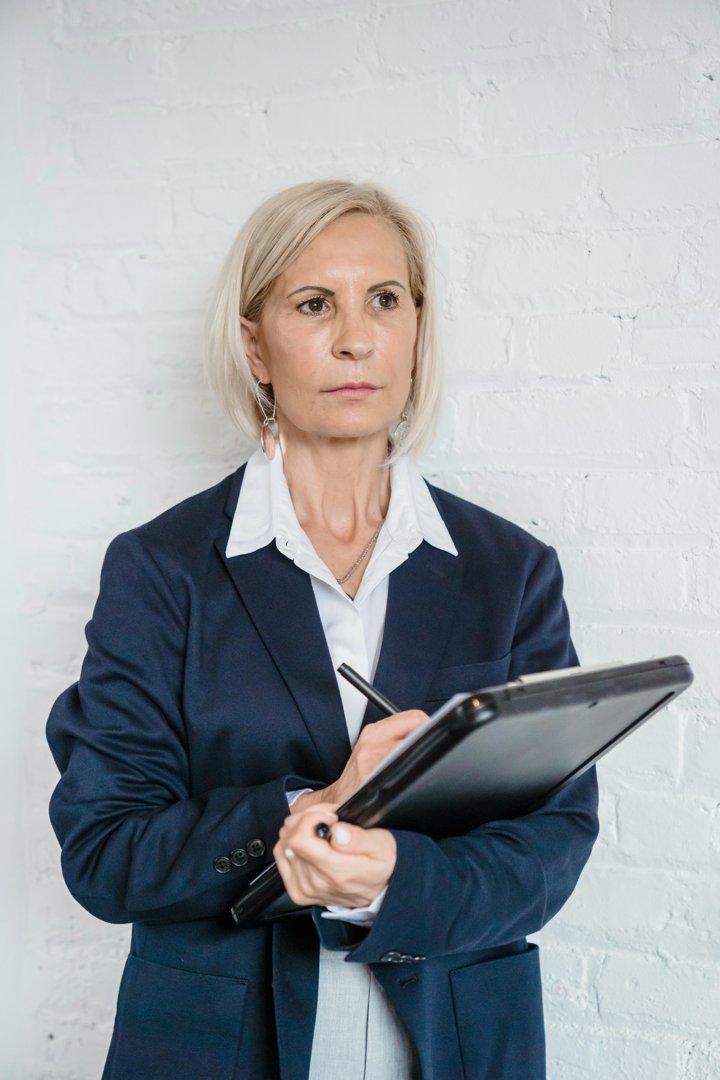 An older woman holding a notepad | Source: Pexels