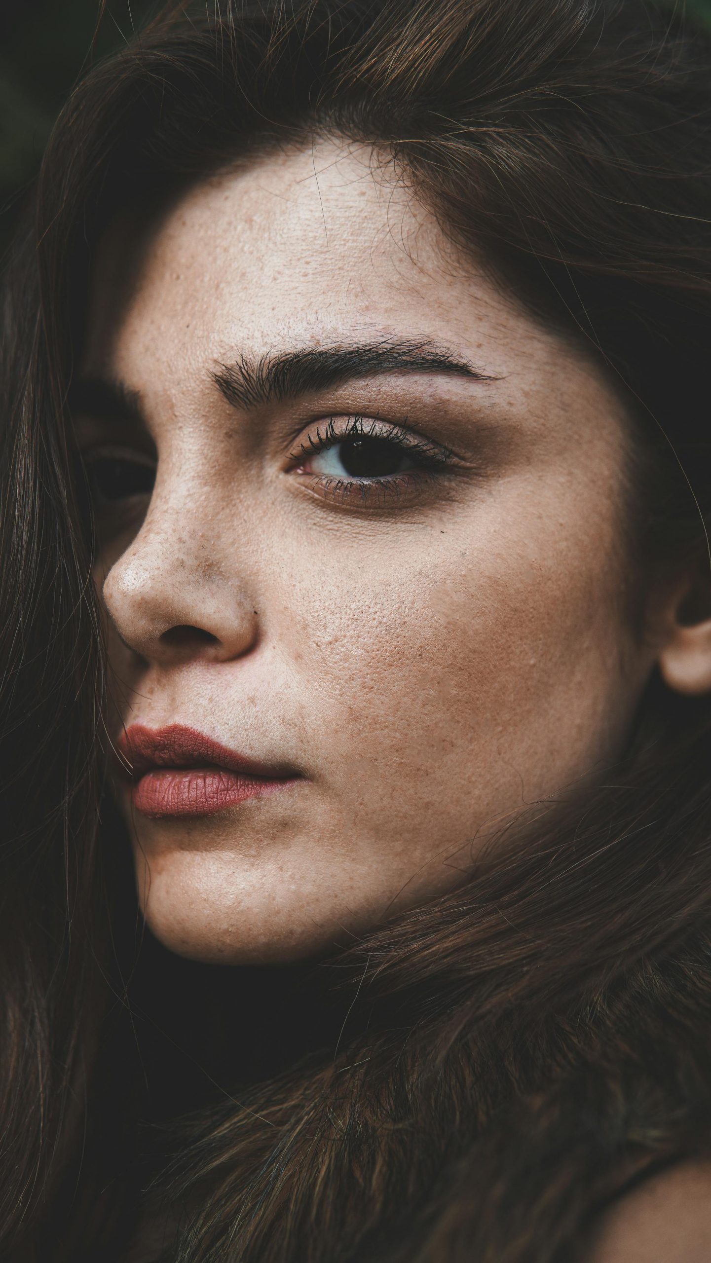 A woman with freckles looking off to the side | Source: Pexels