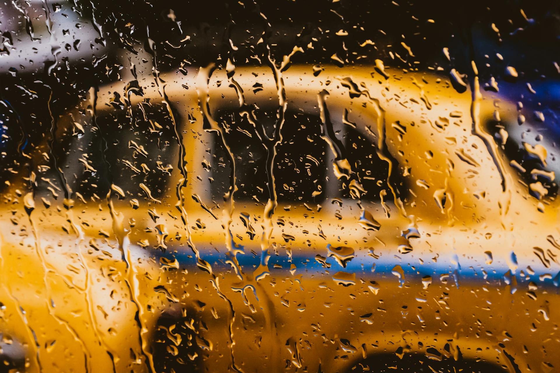 A wet window with a blurred yellow car behind it | Source: Pexels