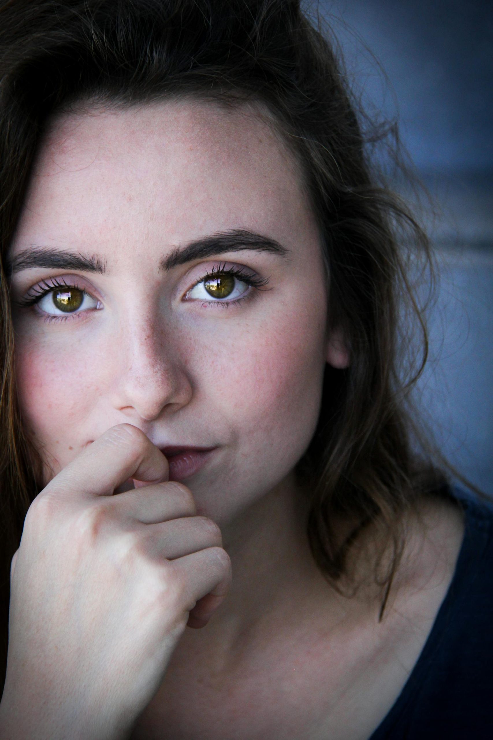A brown-haired woman with green eyes holding her finger to her lips | Source: Pexels