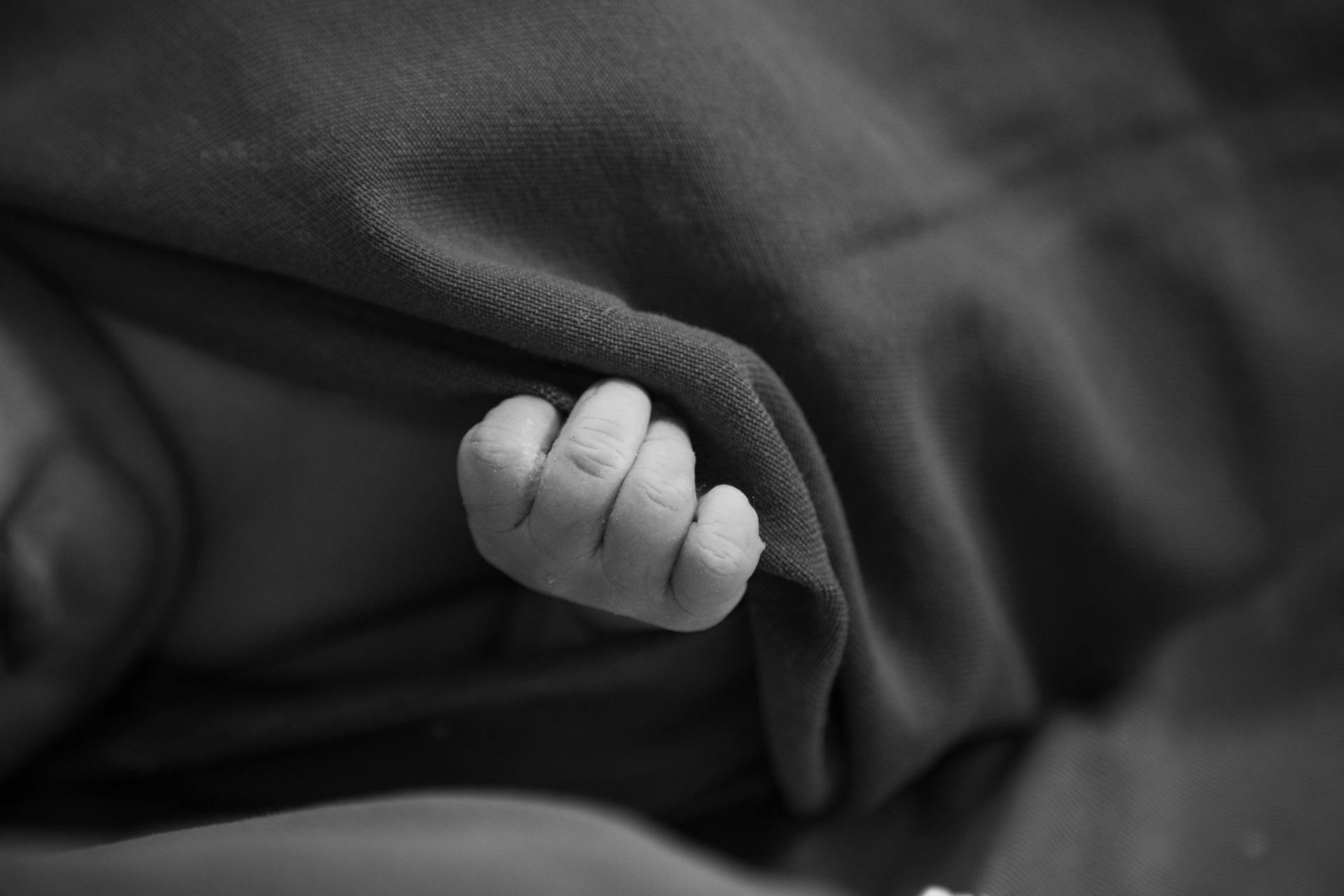 A baby's tiny hand holding onto a blanket | Source: Pexels