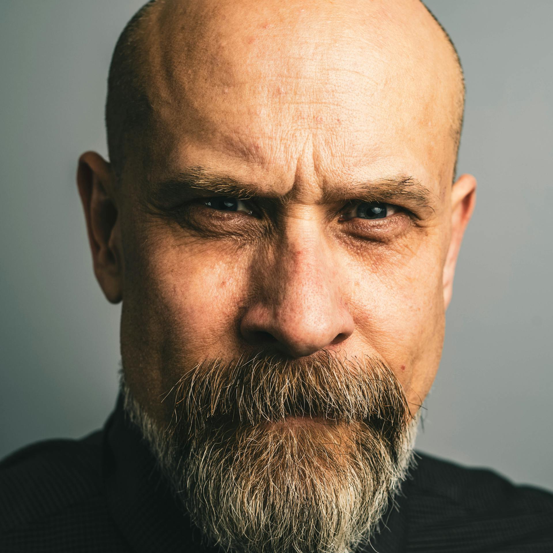 A serious bald man with a beard and mustache looking forward | Source: Pexels