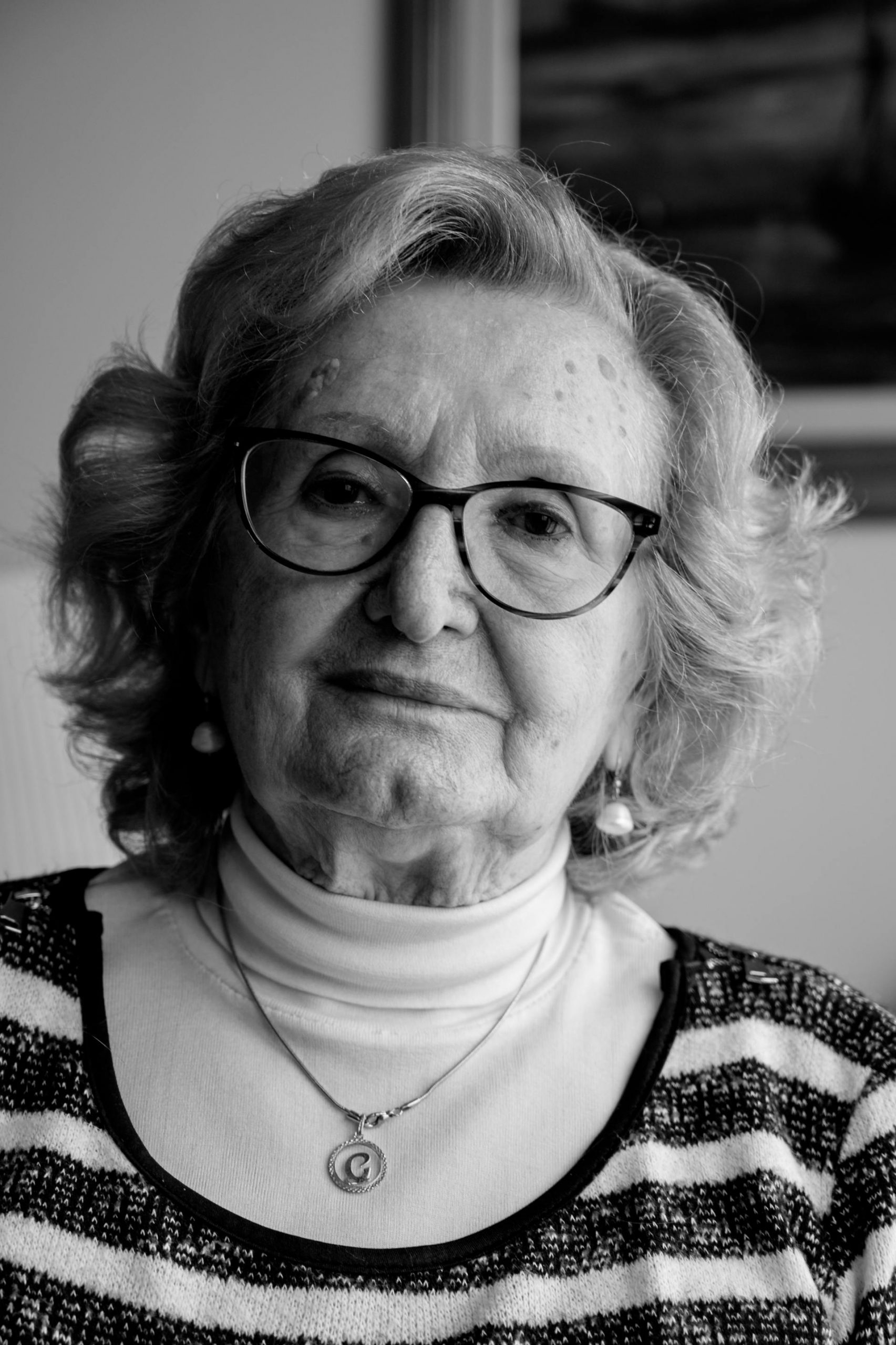 A black-and-white portrait of an elderly woman wearing glasses and a striped sweater | Source: Pexels