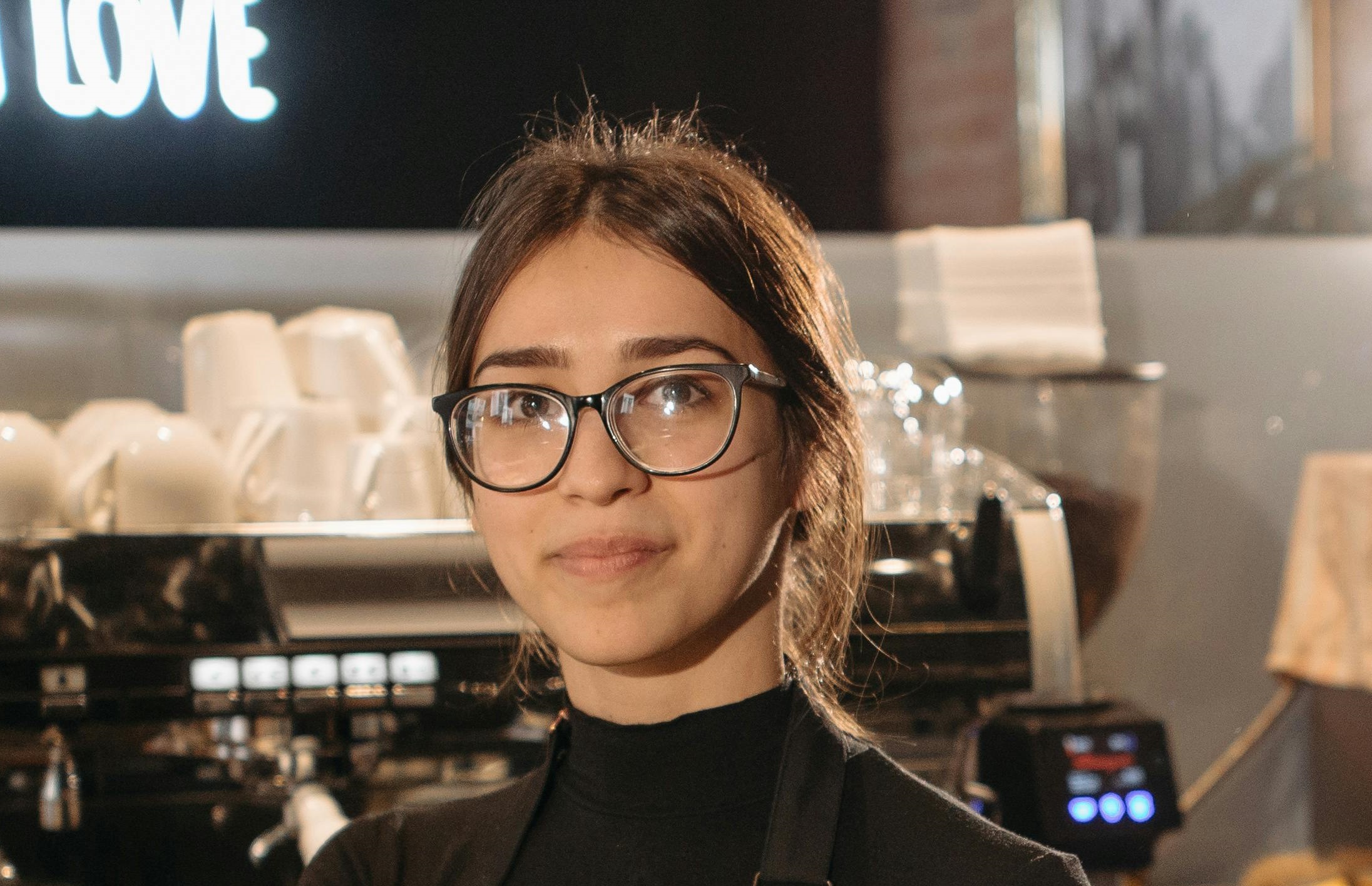 A happy waitress with glasses looking into the distance while standing in a café | Source: Pexels