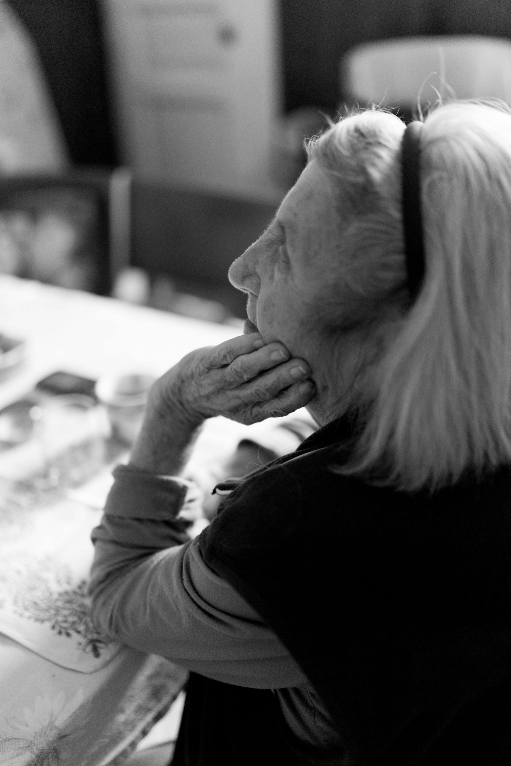 A black-and-white side-profile image of an elderly woman resting her chin on her hand and looking up | Source: Pexels