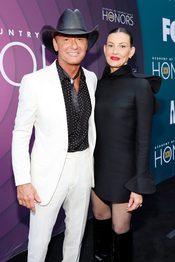At the Academy of Country Music Honors, Tim McGraw stands out in an all-white suit, while Faith Hill grabs attention in a bold black mini dress and over-the-knee boots. The couple's confident pose makes a strong impression on the red carpet.