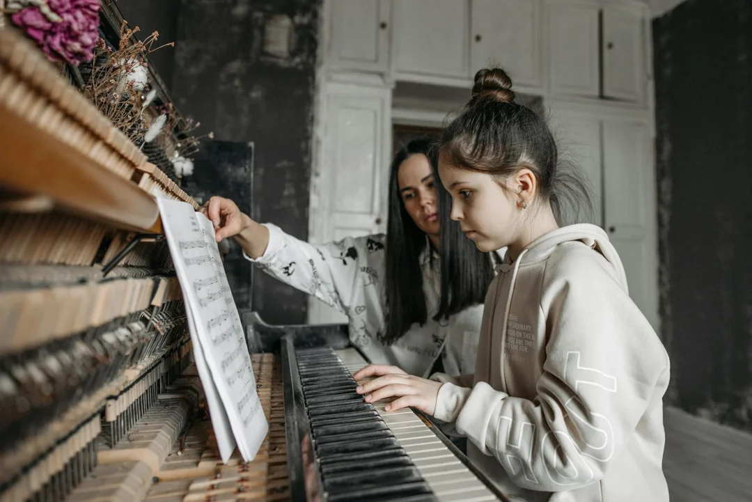 A girl playing the piano with her mother | Source: Pexels