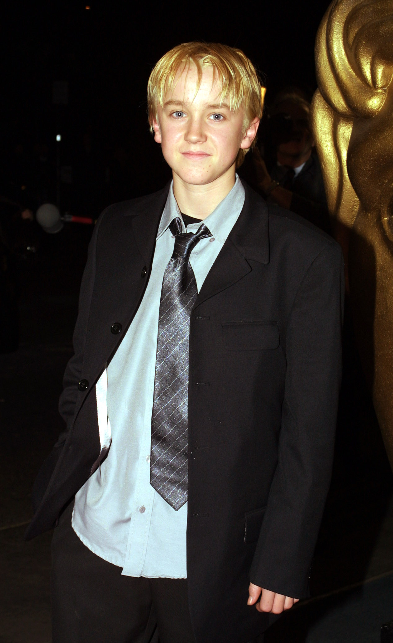 Tom Felton steps into the spotlight with youthful confidence, his blond hair and sharp suit giving him a polished yet boyish charm. His loosened tie and easy smile hint at a night of celebration rather than formality. Arriving at the British Academy Children’s Film & Television Awards, he carries the energy of a rising star enjoying every moment.