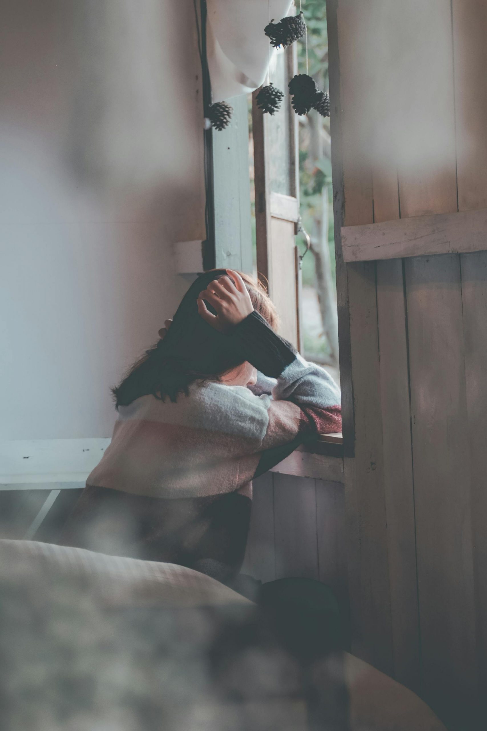 A distraught woman leaning on a wooden window | Source: Pexels