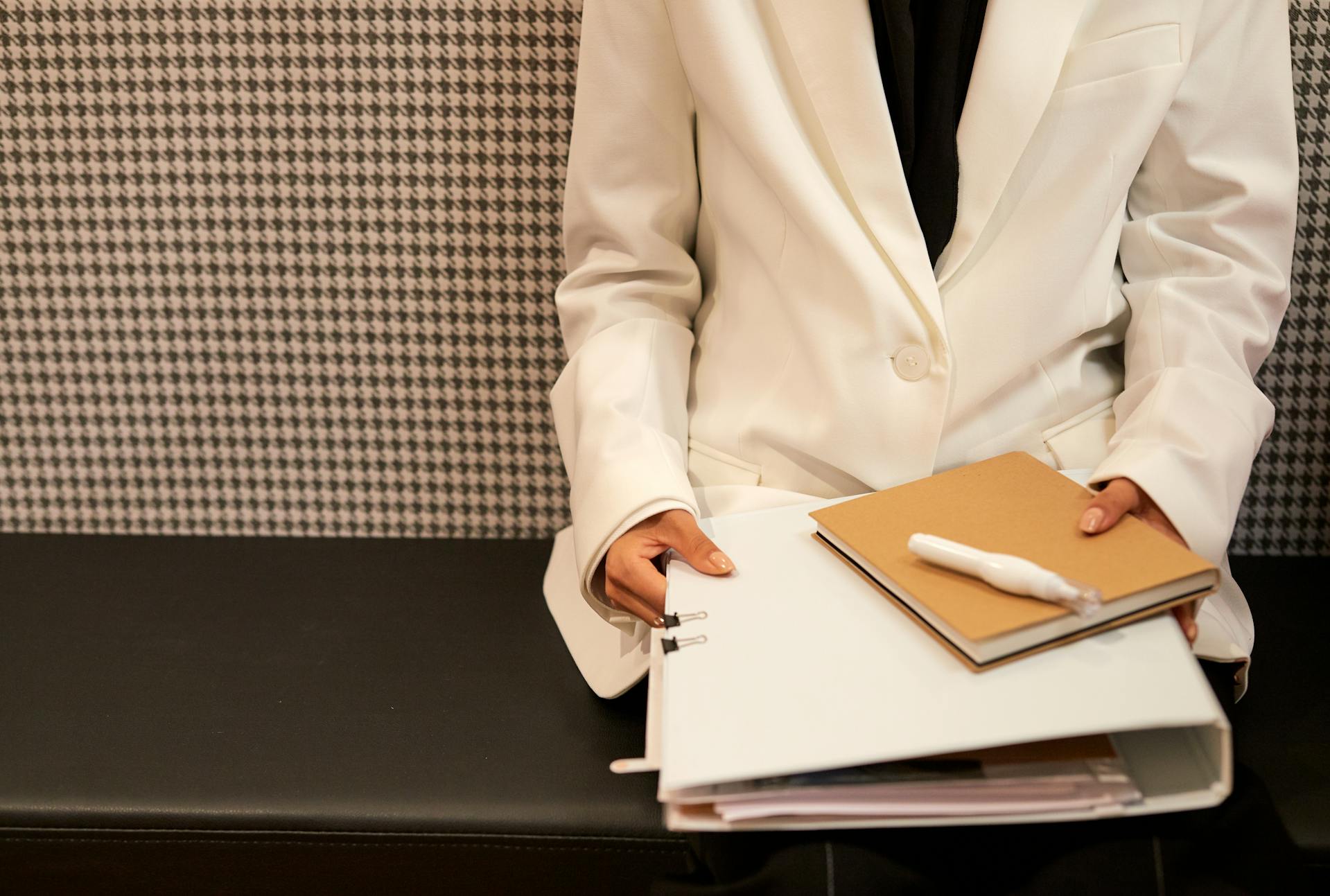 A woman in a white coat holding a folder of documents | Source: Pexels
