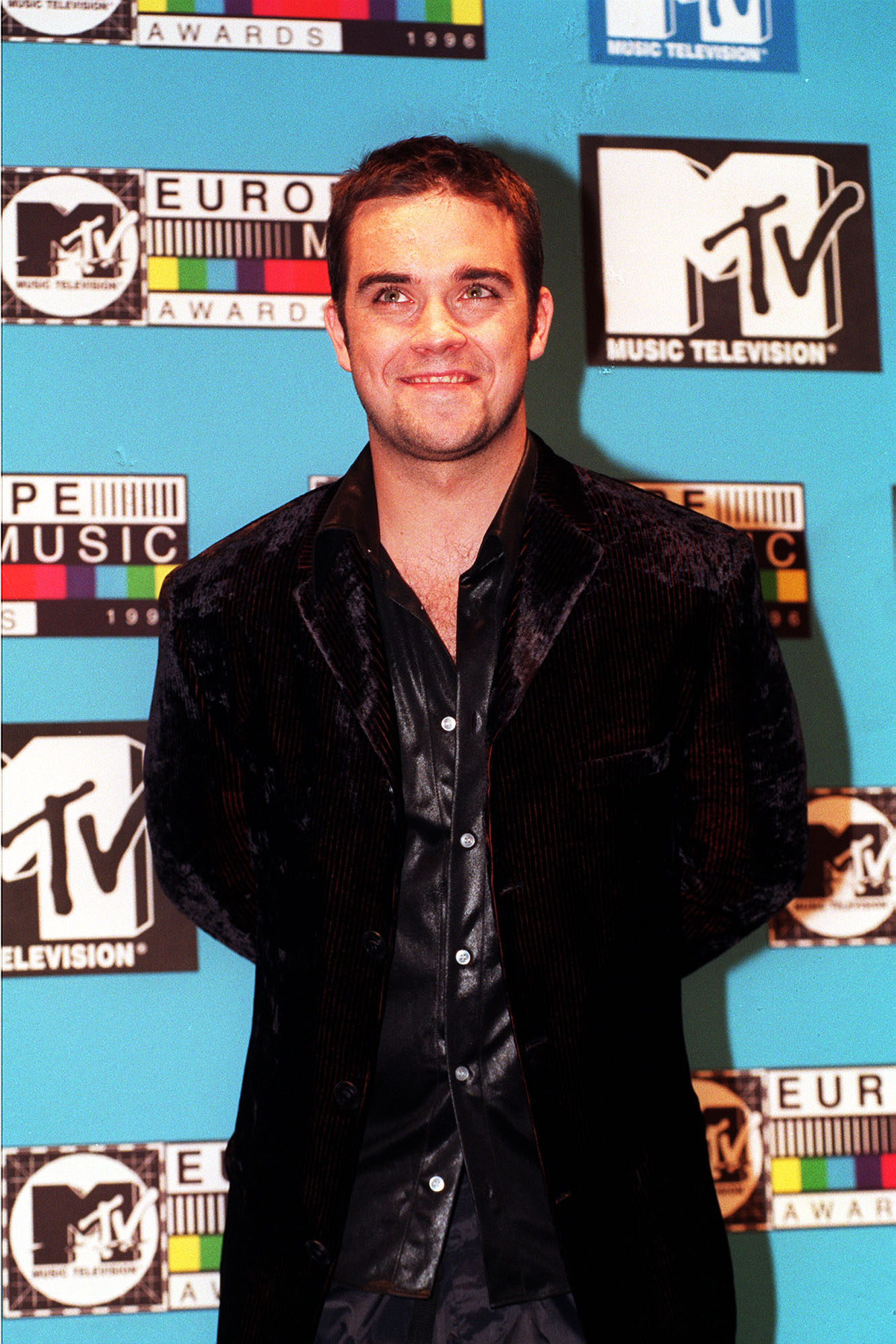 Robbie Williams attended the MTV Europe Music Awards in 1996, dressed in a velvet blazer and satin shirt. The appearance marked one of his early solo milestones, as he began stepping out of Take That's shadow and carving out his own path in pop music.