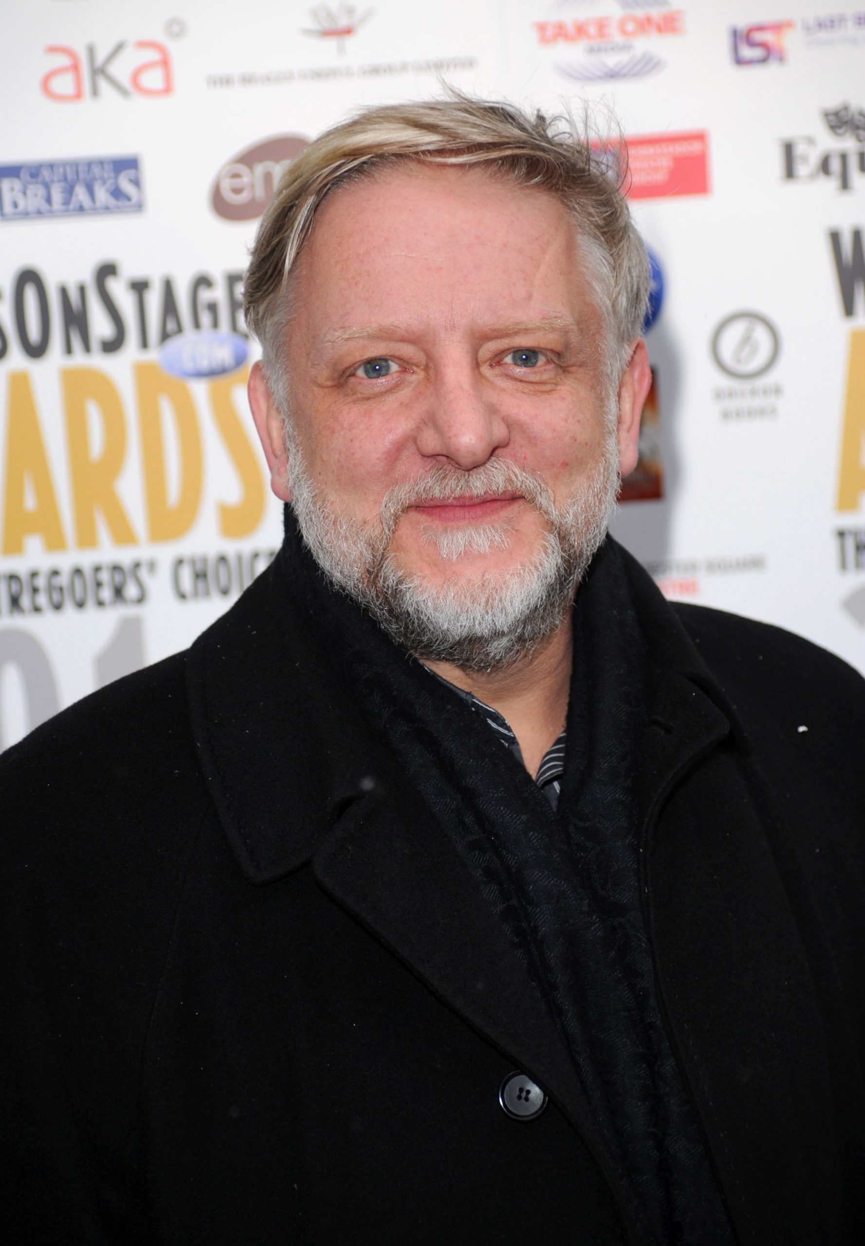 Simon Russell Beale attended the Whatsonstage.com Awards Concert Launch on December 3, 2010, in London, England, wearing a black overcoat and scarf. With his signature silver beard and friendly demeanor, he posed warmly for photos at the theater-focused fan-voted event.