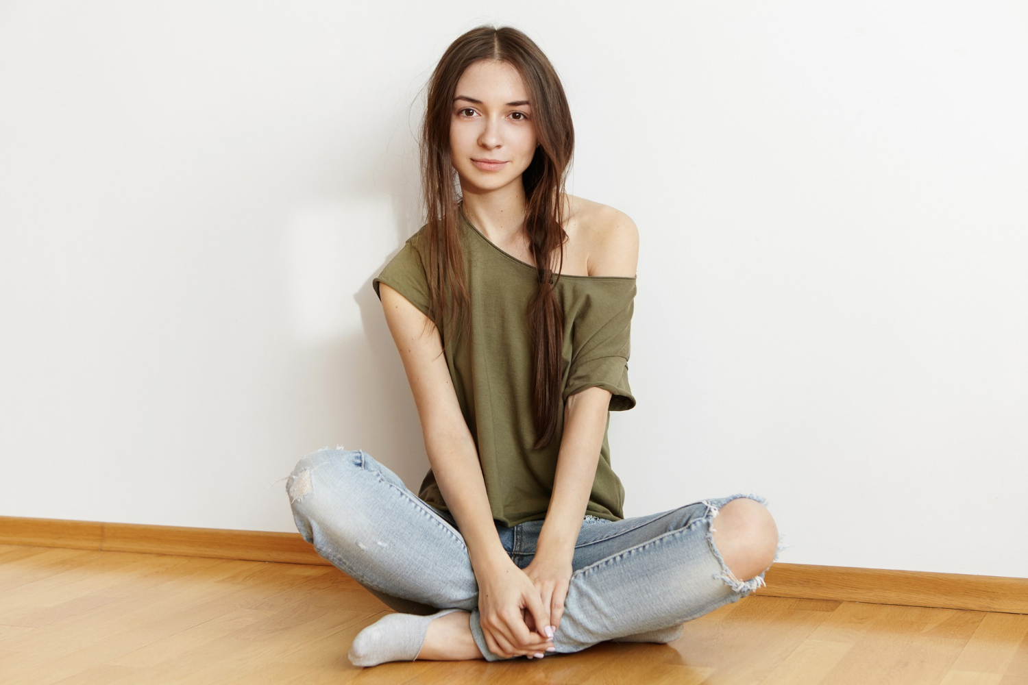 A cheerful teenage girl sitting on the floor and smiling | Source: Freepik