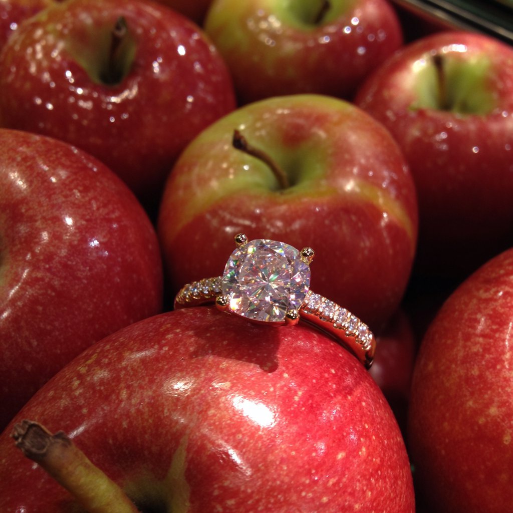 A diamond ring in an apple display at the store | Source: Midjourney
