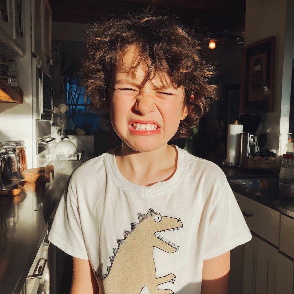 A grimacing little boy standing in a kitchen | Source: Midjourney