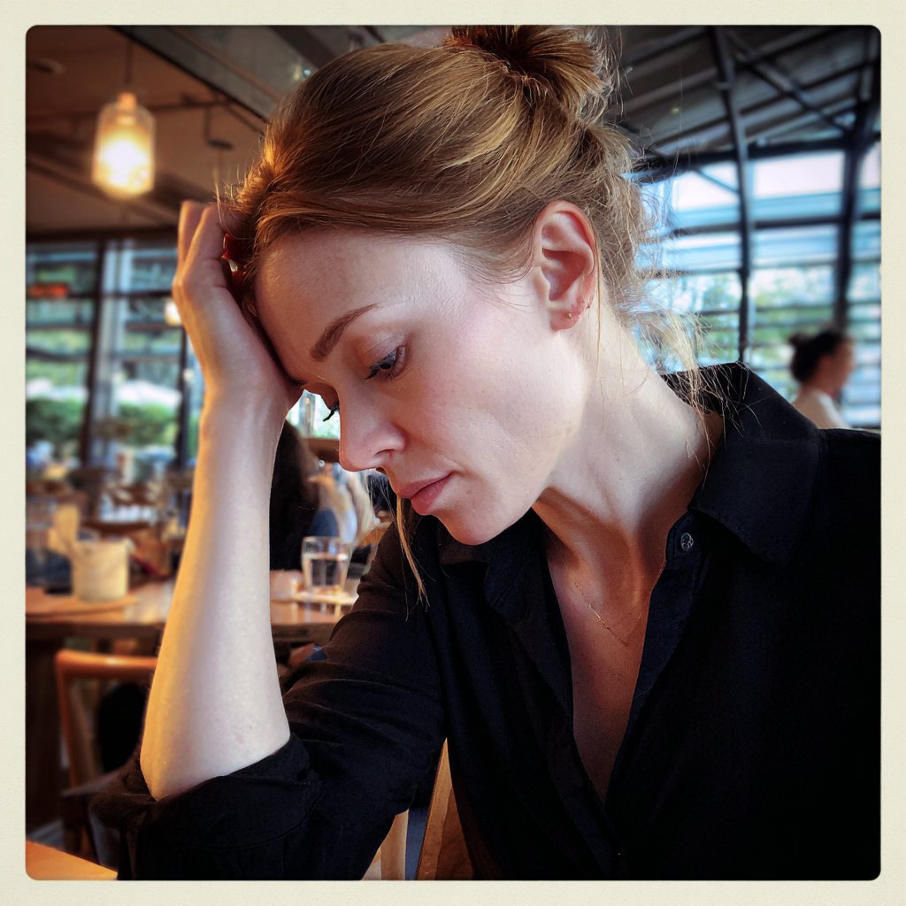 A woman sitting with her hand on her head | Source: Midjourney