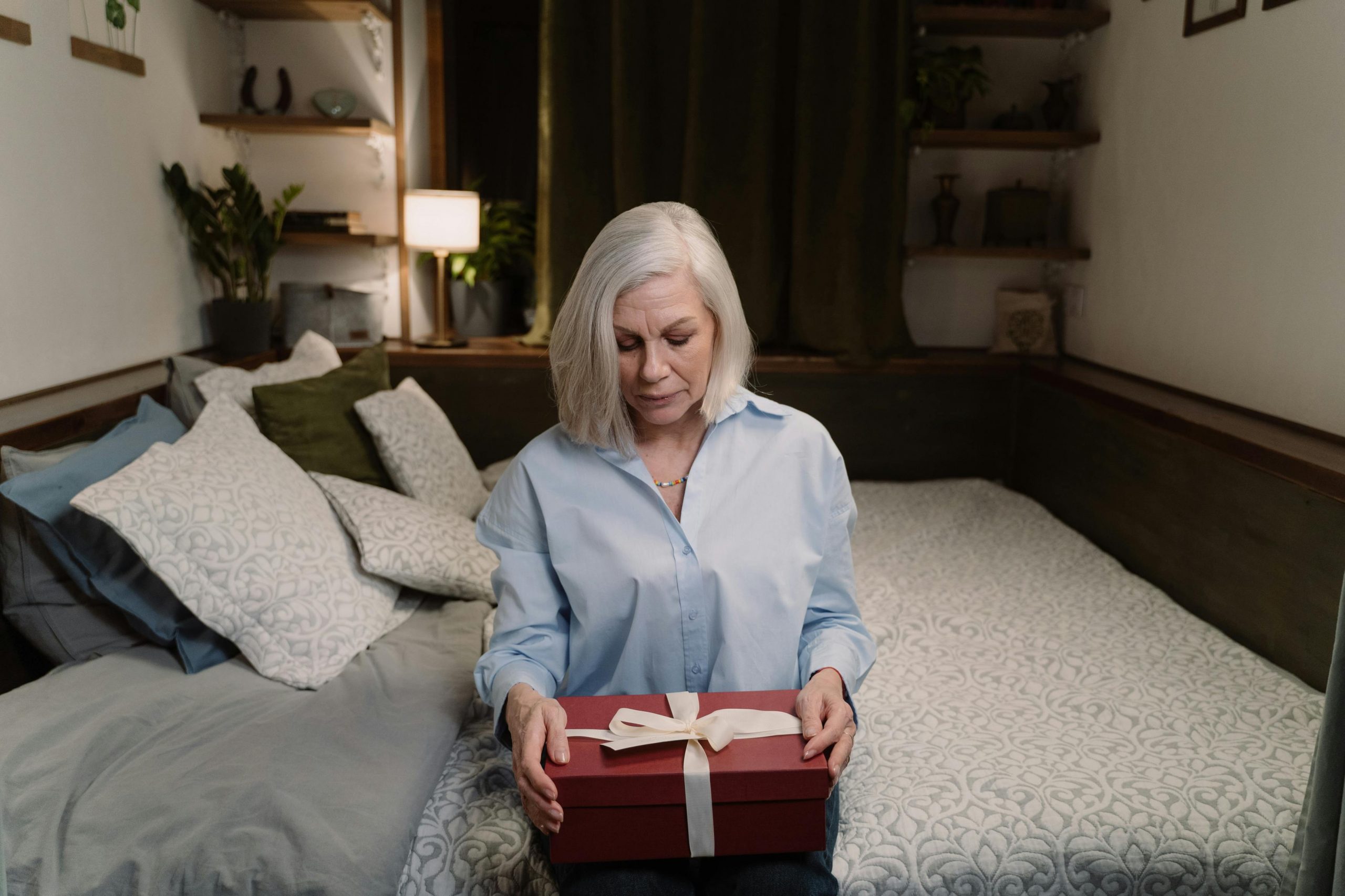 A woman holding a box while seated on a bed | Source: Pexels