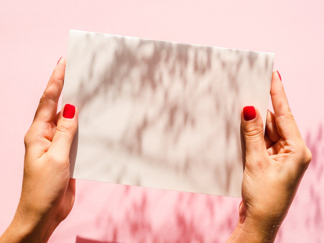 A woman holding a sheet of paper | Source: Freepik