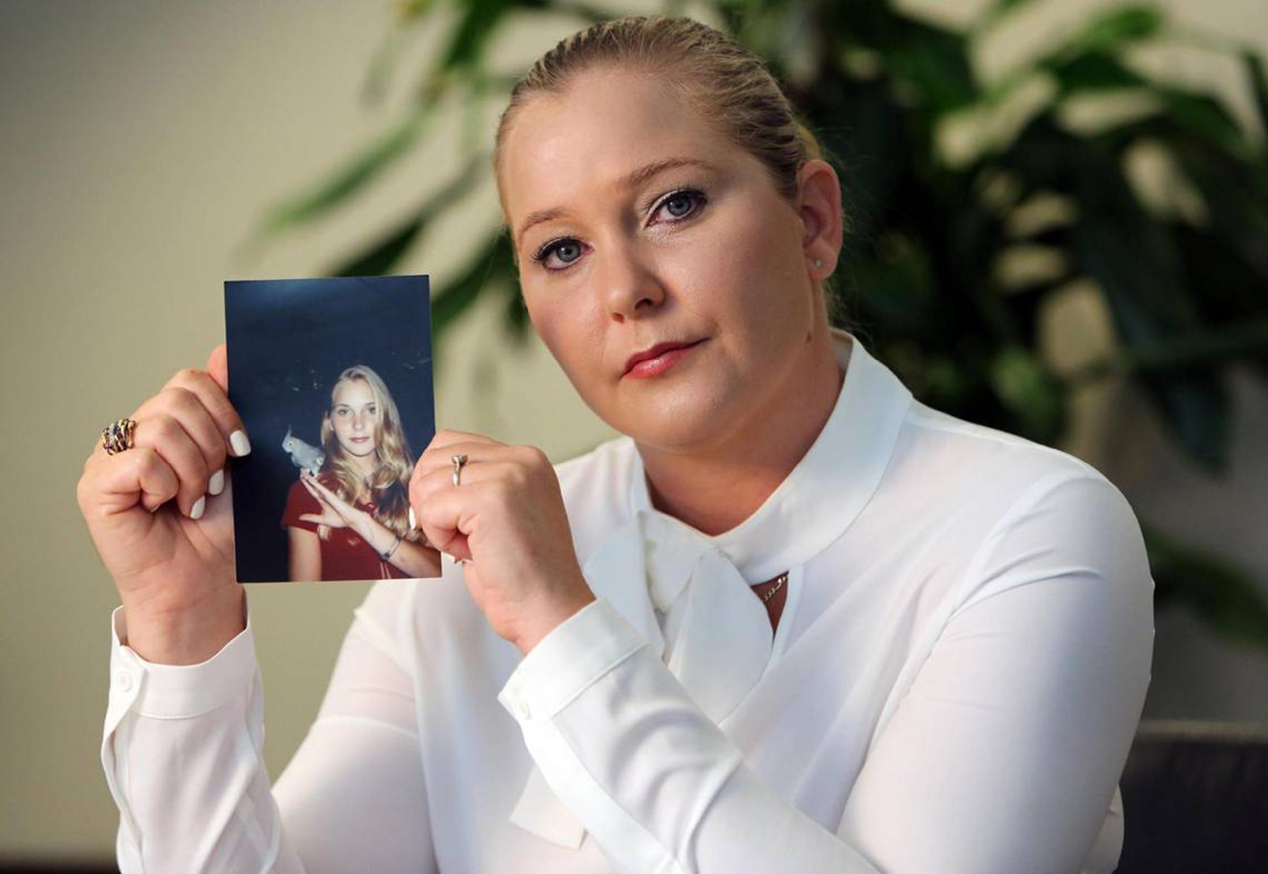 Virginia Giuffre photographed in 2022 with a photo of herself as a teenager. | Source: Getty Images